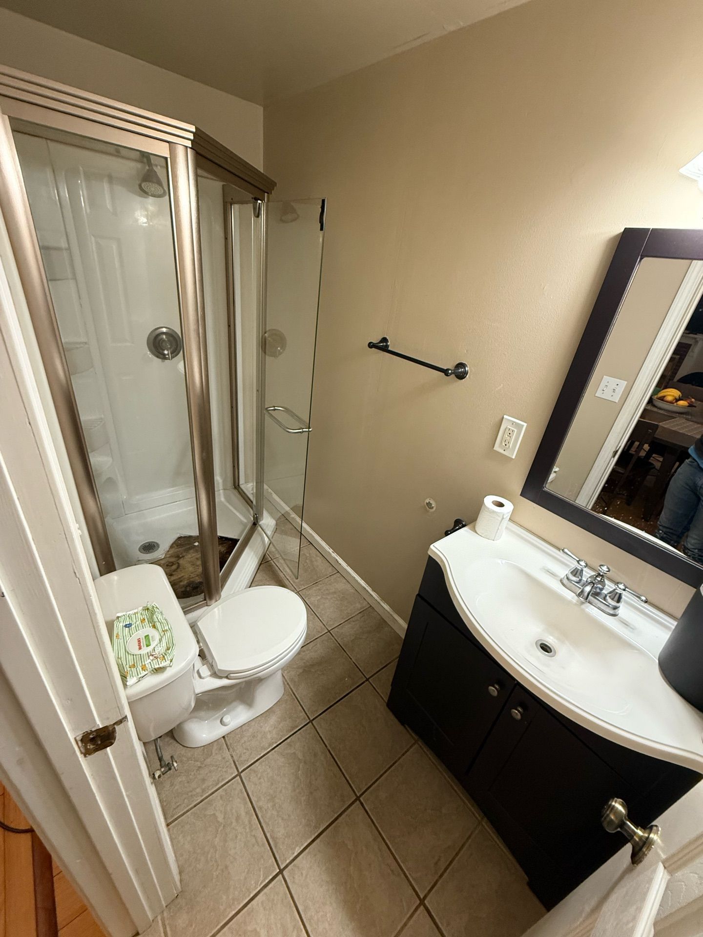 A bathroom with a toilet , sink , shower and mirror.