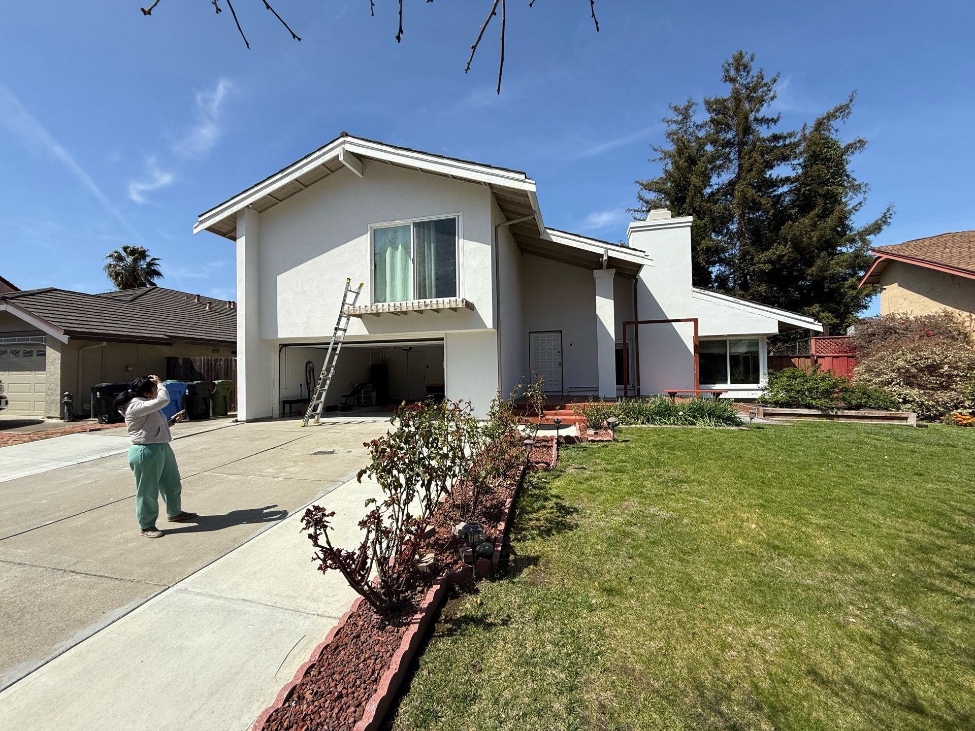 A man is standing in front of a house that is being painted