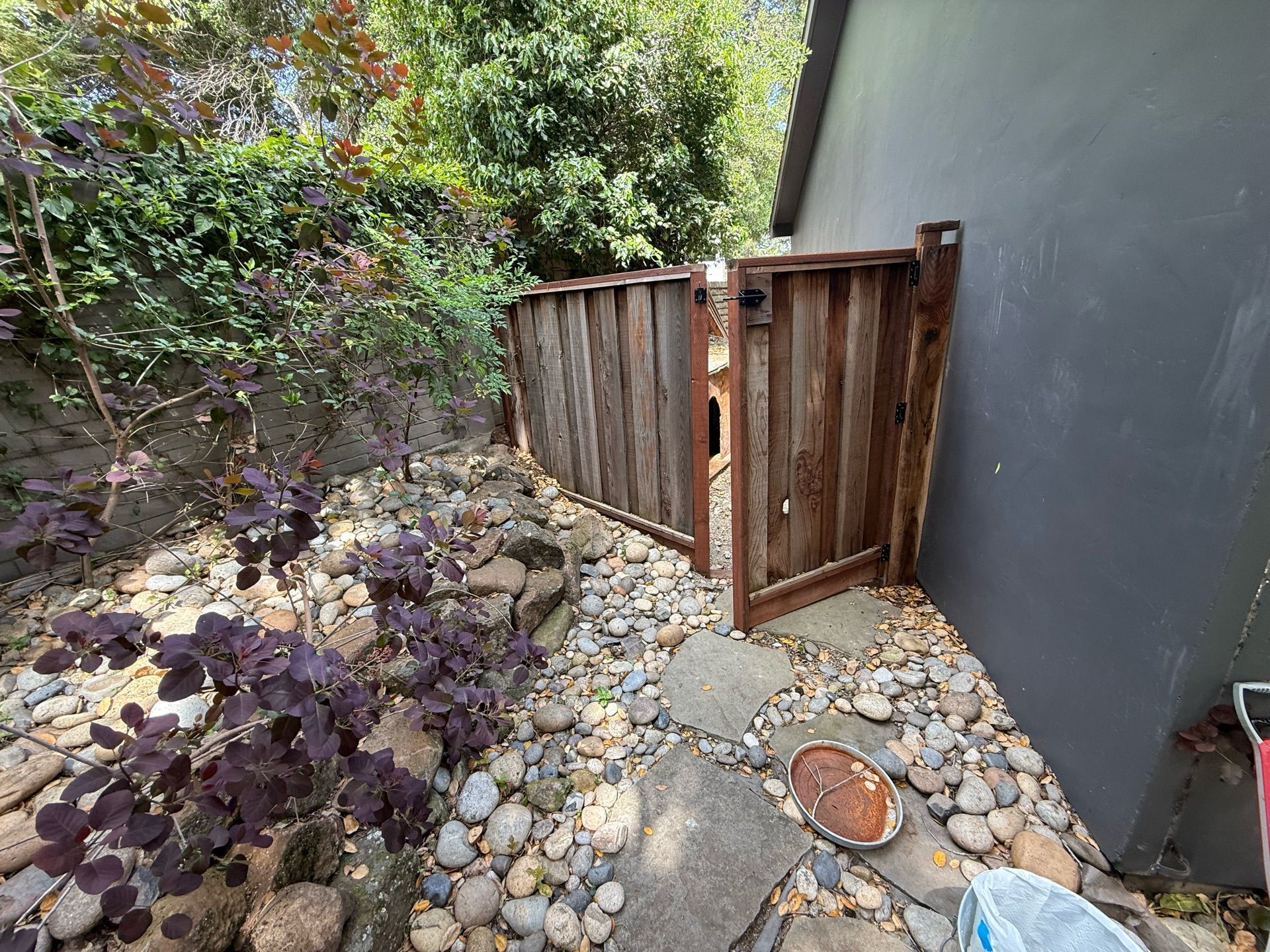 A wooden fence is surrounded by rocks and plants in a garden.