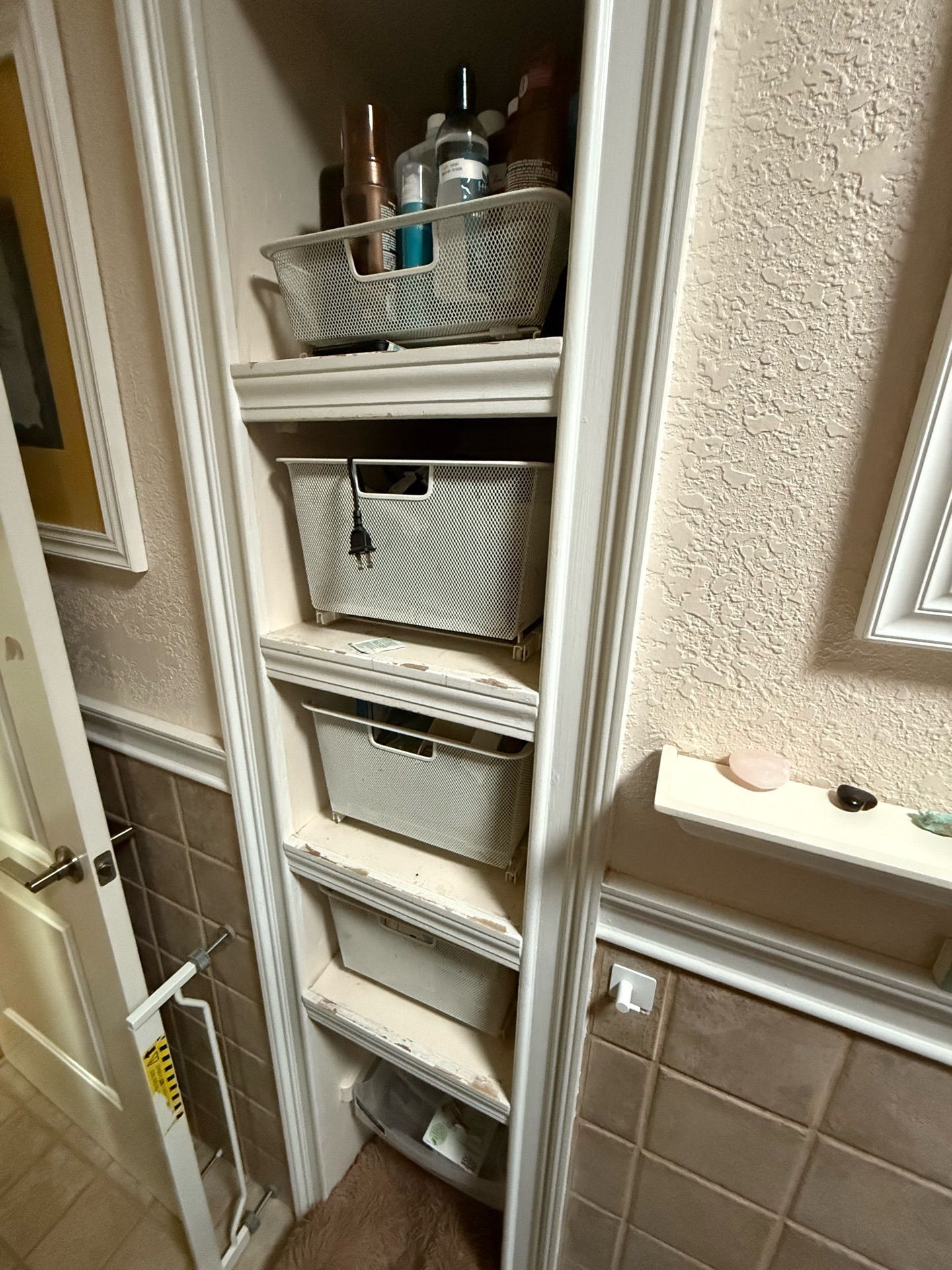 A bathroom closet filled with baskets and bottles.