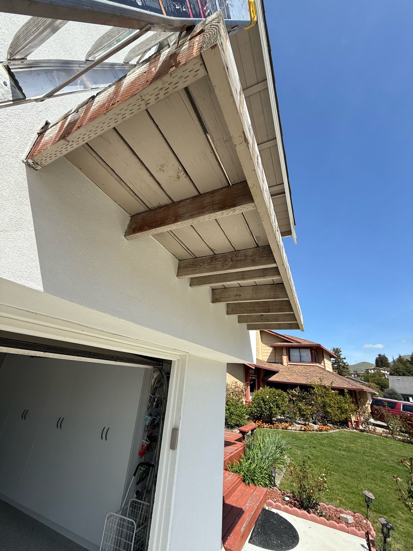 A white house with a wooden roof and a garage door.