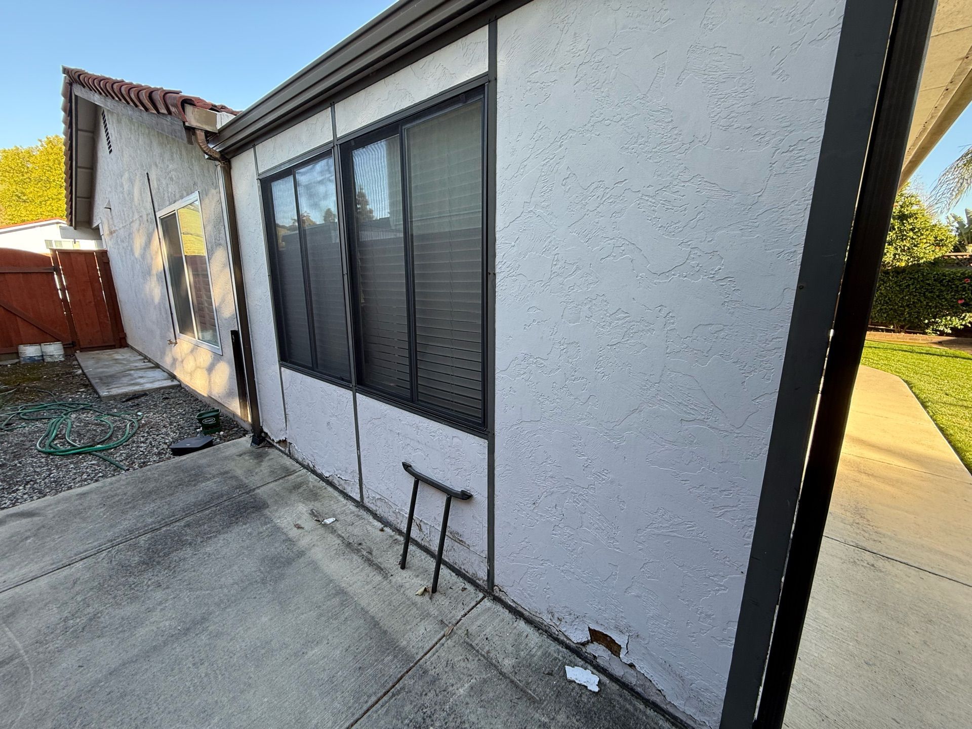 The side of a house with a lot of windows and a concrete walkway.