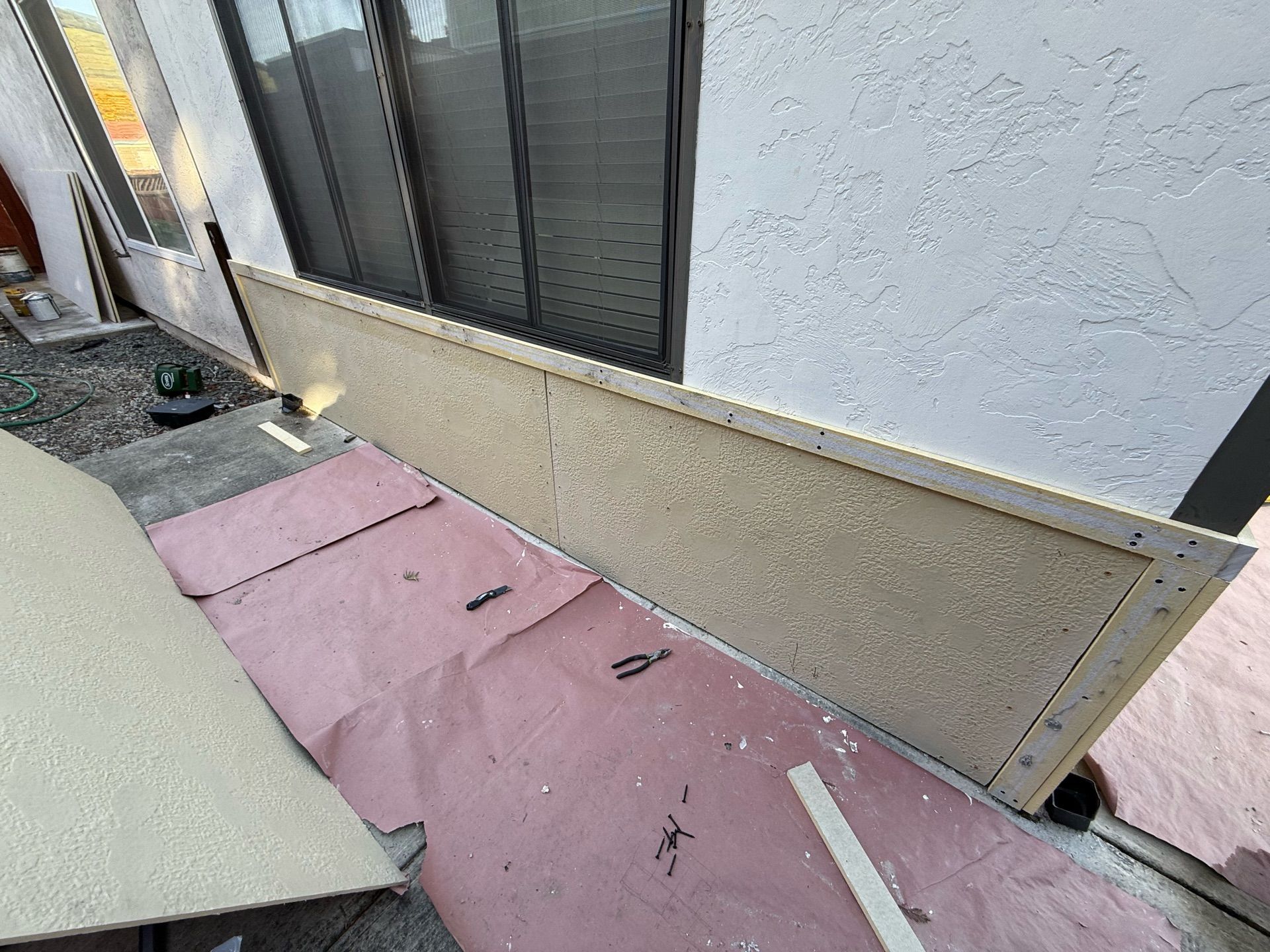 A large piece of wood is sitting on the ground next to a window.