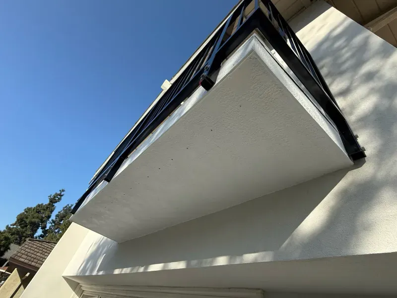 A balcony on the side of a building with a blue sky in the background