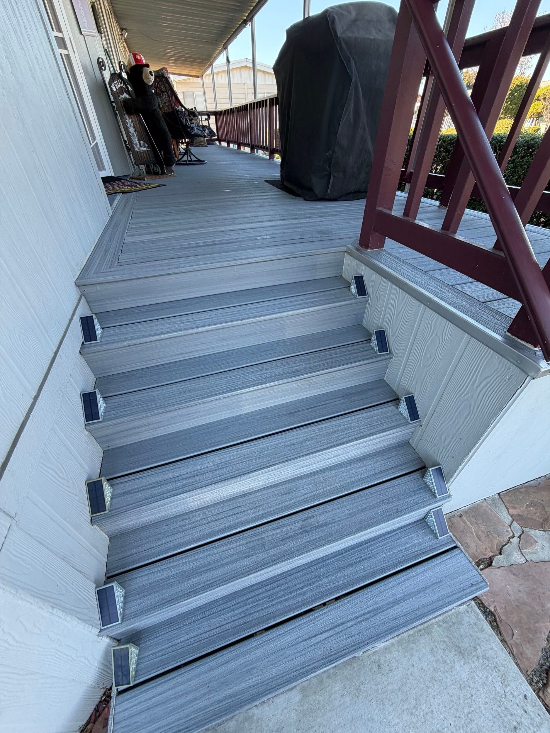 Composite deck remodel featuring gray low-maintenance decking boards, upgraded stair system with integrated step lighting, refreshed porch surface, and improved outdoor living functionality. Exterior renovation completed by Dream Build Services, specializing in deck replacement, composite decking installation, porch remodeling, and residential exterior upgrades in the Bay Area.