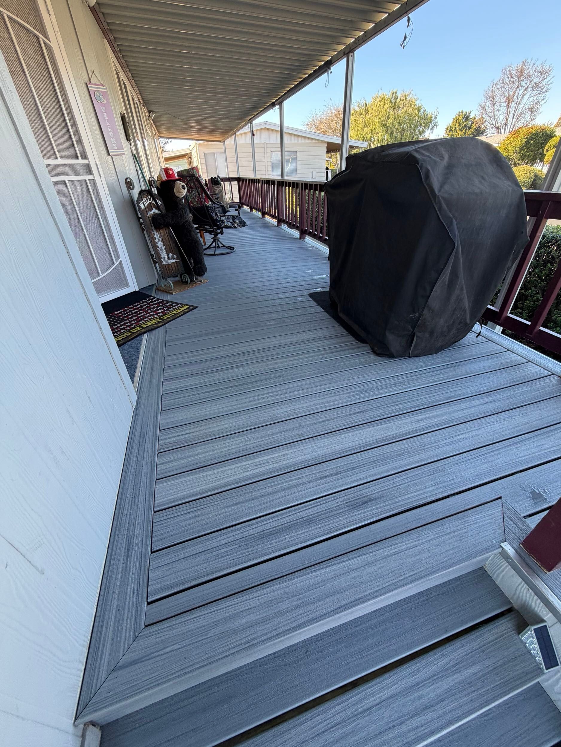 Composite deck remodel featuring gray low-maintenance decking boards, upgraded stair system with integrated step lighting, refreshed porch surface, and improved outdoor living functionality. Exterior renovation completed by Dream Build Services, specializing in deck replacement, composite decking installation, porch remodeling, and residential exterior upgrades in the Bay Area.