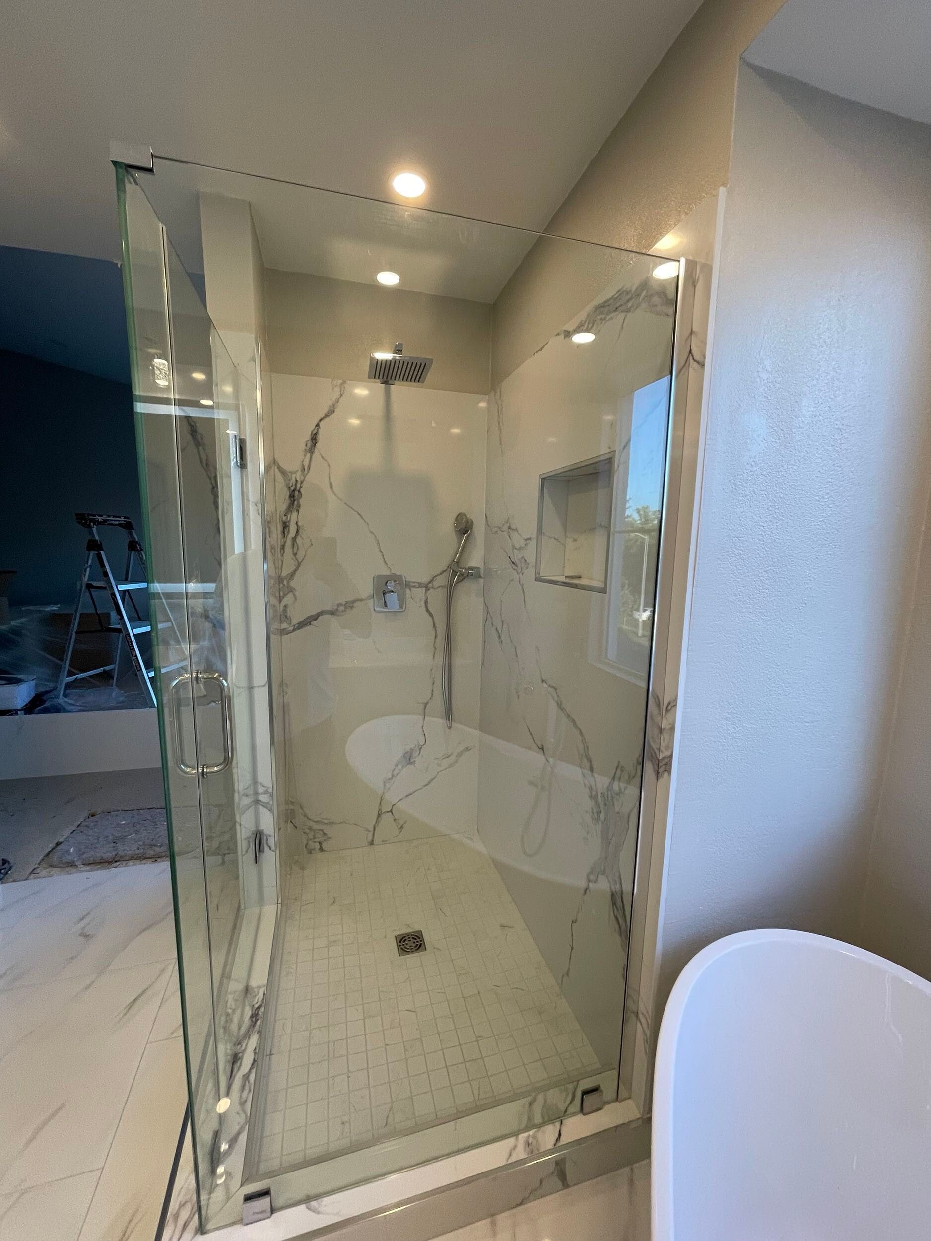 Luxury master bathroom remodel featuring a freestanding soaking tub by a large picture window, dual vessel sinks on a sleek white vanity, illuminated LED backlit mirror, recessed lighting, marble-look porcelain flooring, and frameless glass shower — custom design by Dream Build Services in the Bay Area.