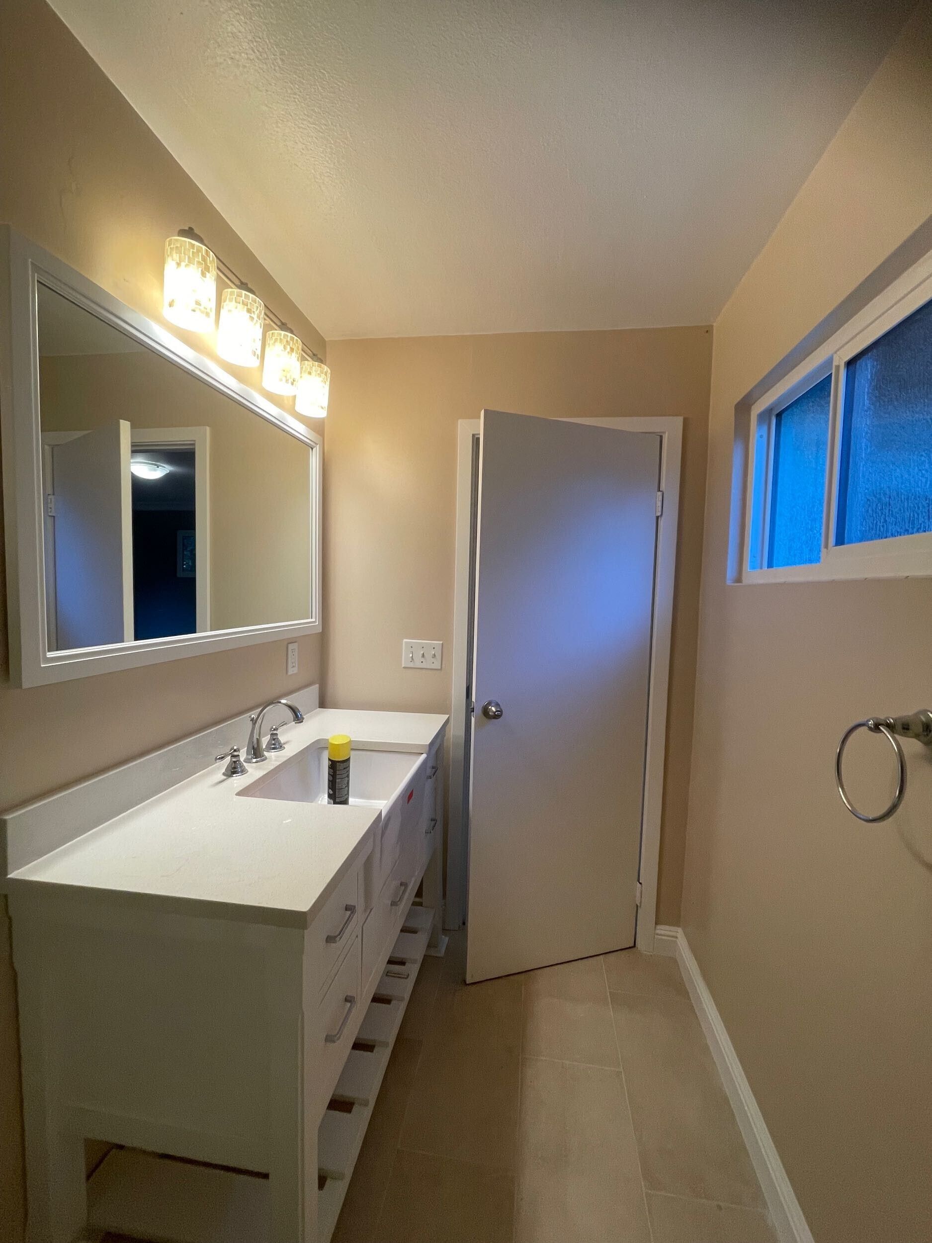 Complete bathroom remodel transformation showcasing before-and-after renovation. The updated space features a modern soaking tub with aqua subway tile walls, sleek white vanity with double sinks, bright lighting fixtures, and upgraded flooring. Project includes plumbing upgrades, custom tile shower niche, and improved storage with built-in cabinetry. Small bathroom remodel in the Bay Area with contemporary design and high-quality finishes by Dream Build Services.