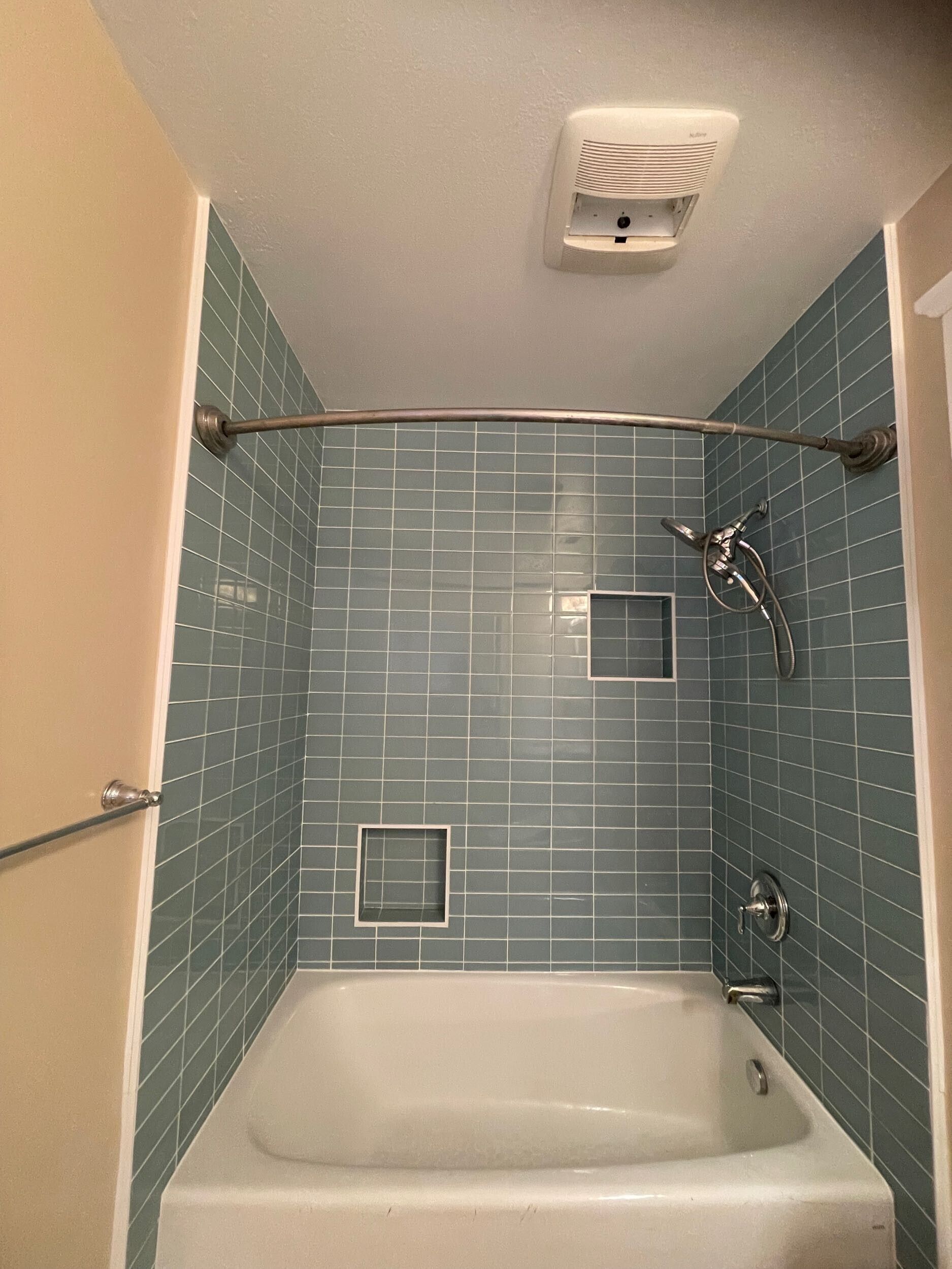 Complete bathroom remodel transformation showcasing before-and-after renovation. The updated space features a modern soaking tub with aqua subway tile walls, sleek white vanity with double sinks, bright lighting fixtures, and upgraded flooring. Project includes plumbing upgrades, custom tile shower niche, and improved storage with built-in cabinetry. Small bathroom remodel in the Bay Area with contemporary design and high-quality finishes by Dream Build Services.