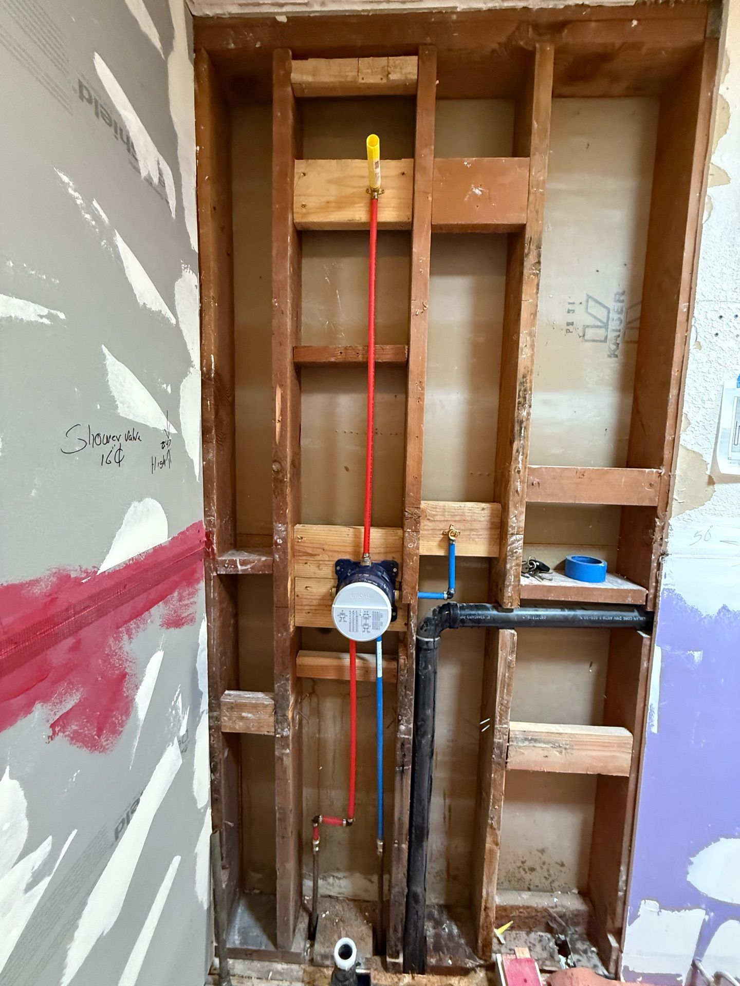 A bathroom under construction with wooden walls and pipes.
