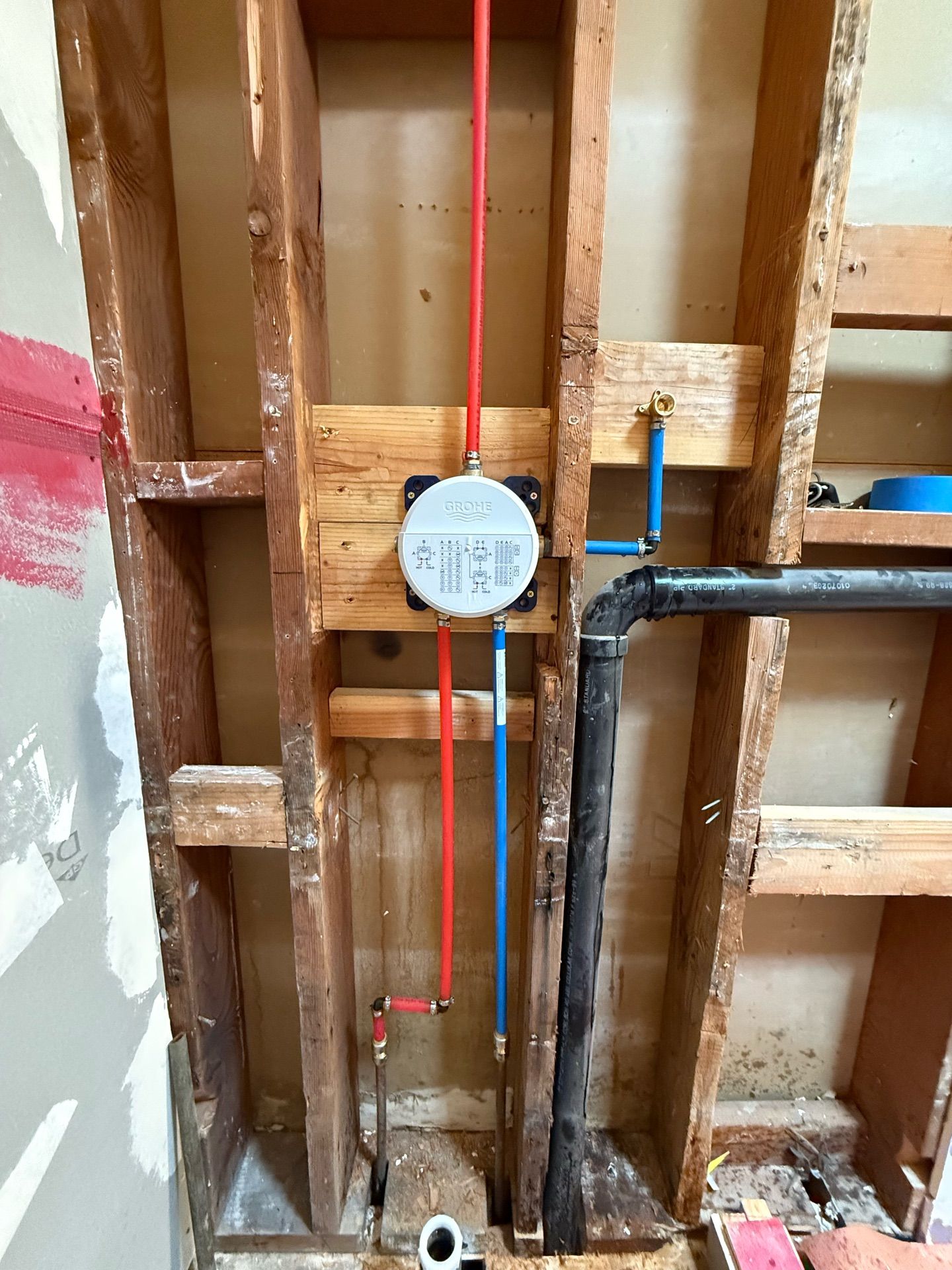 A wooden wall with a faucet and pipes coming out of it.