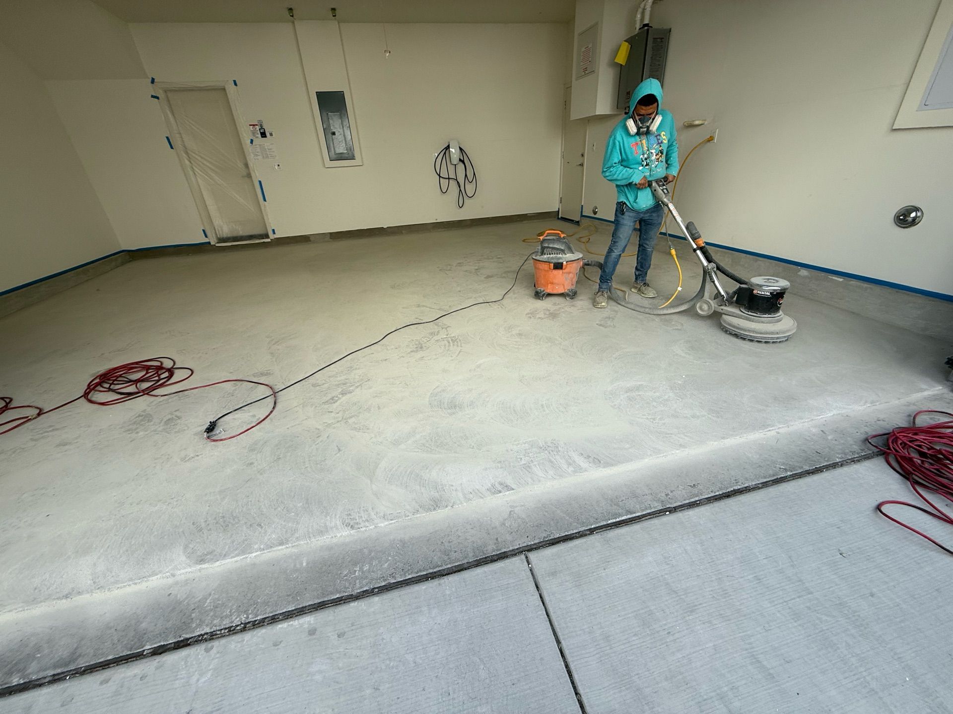 A man is using a vacuum cleaner to clean a concrete floor in a garage.