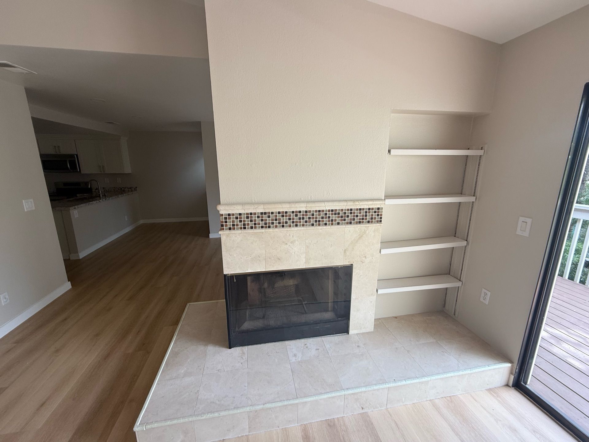 An empty living room with a fireplace and shelves