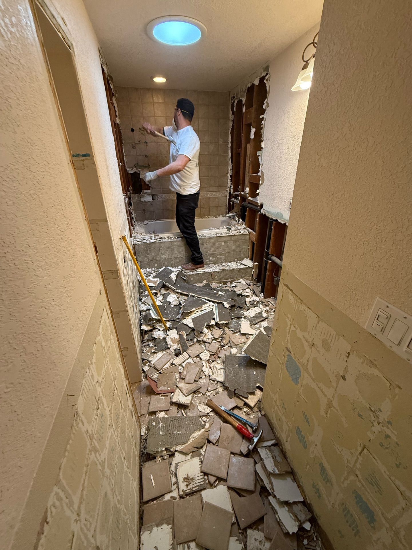A man is standing in a hallway in a bathroom.
