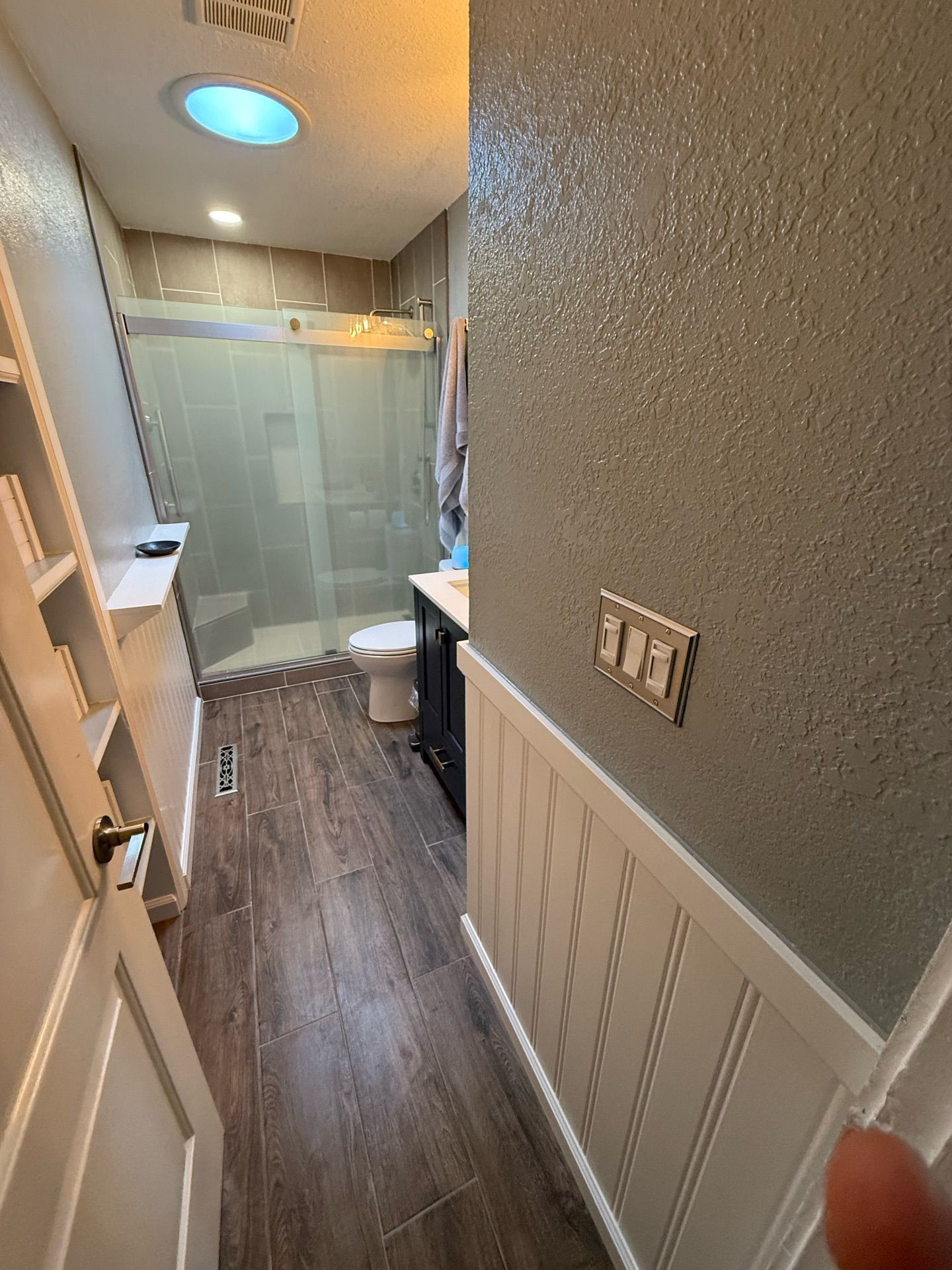 A bathroom with a walk in shower , sink , toilet and skylight.