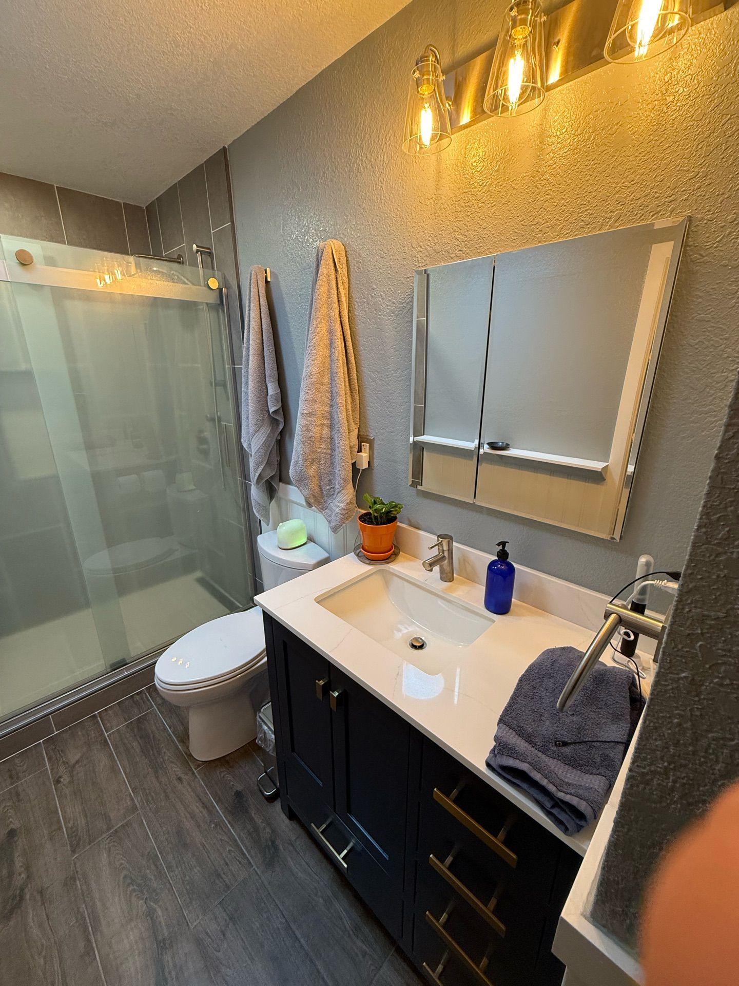 A bathroom with a sink , toilet , shower and mirror.