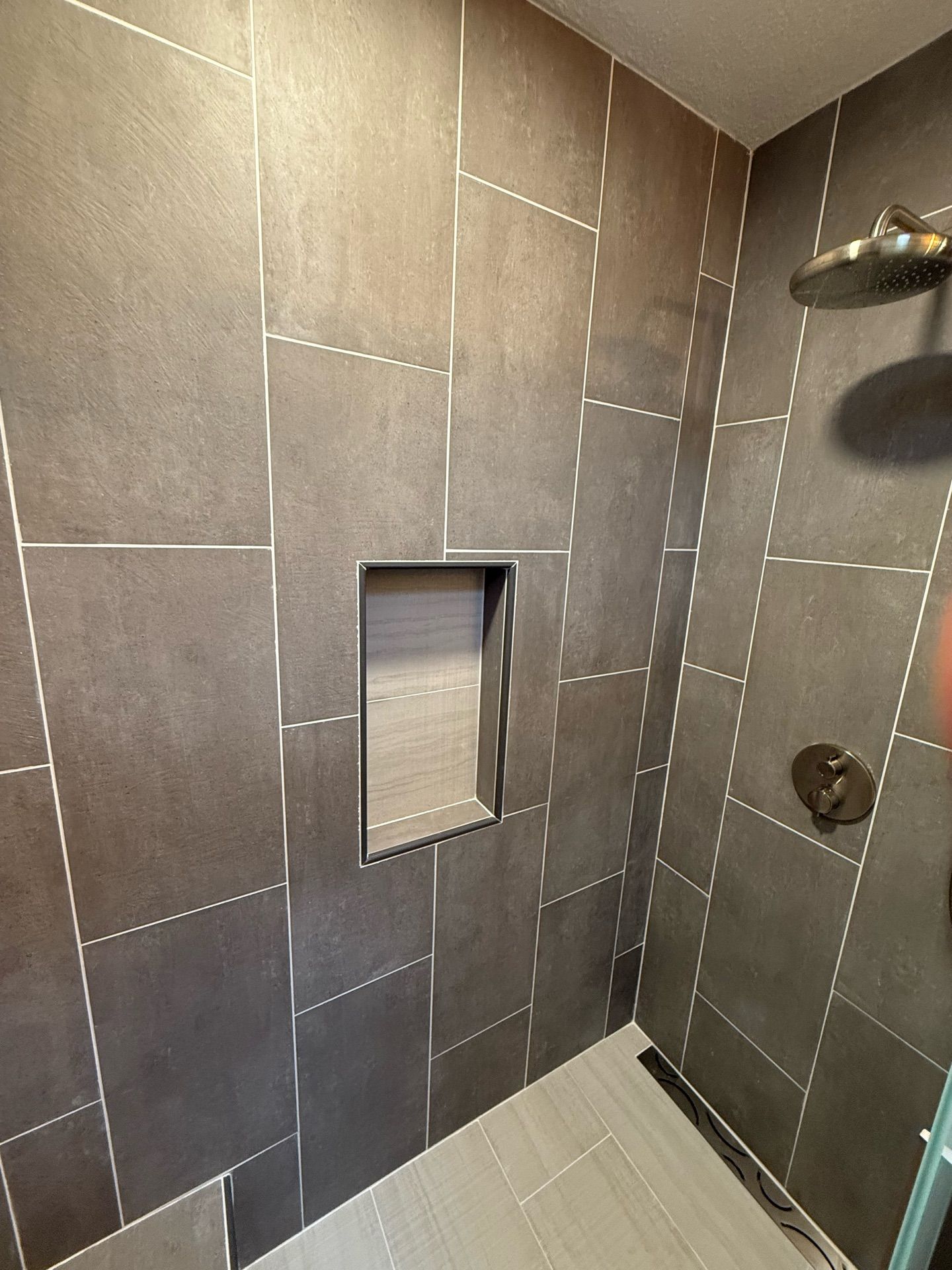 A shower with a niche in the wall and a shower head.