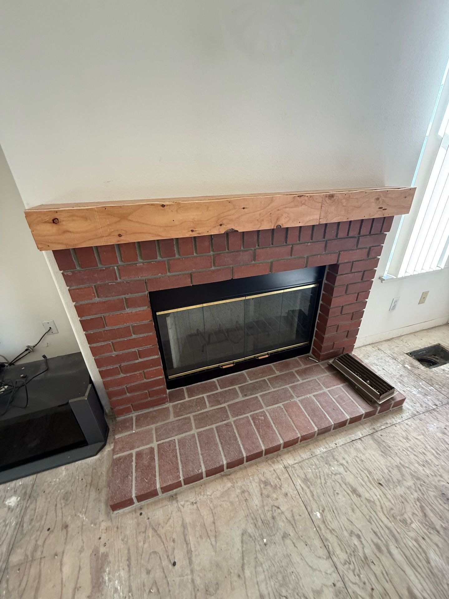 A brick fireplace with a wooden mantle in a living room.