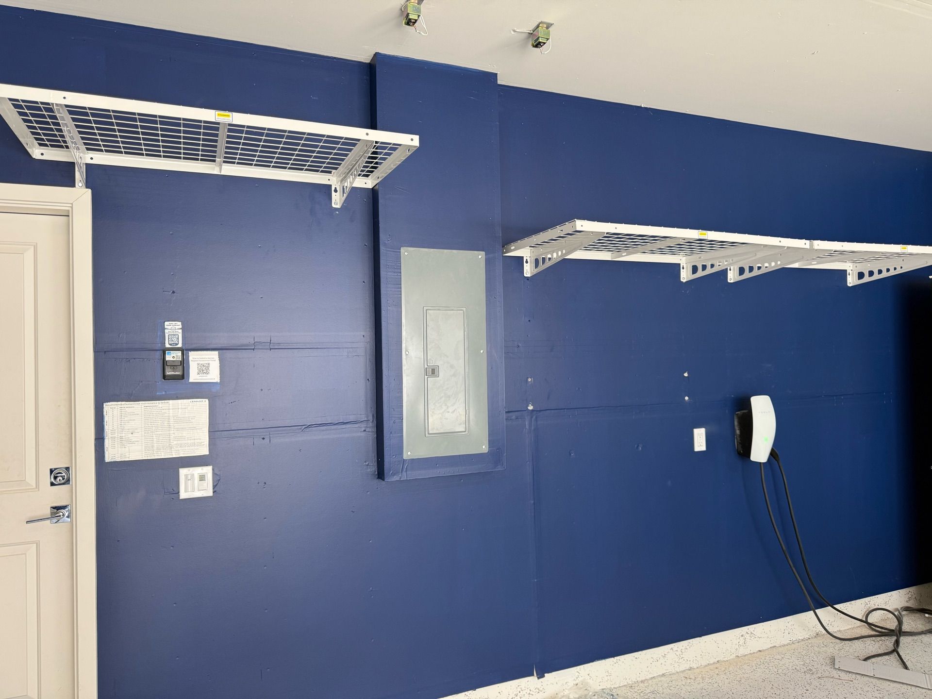 A garage with blue walls and white shelves.