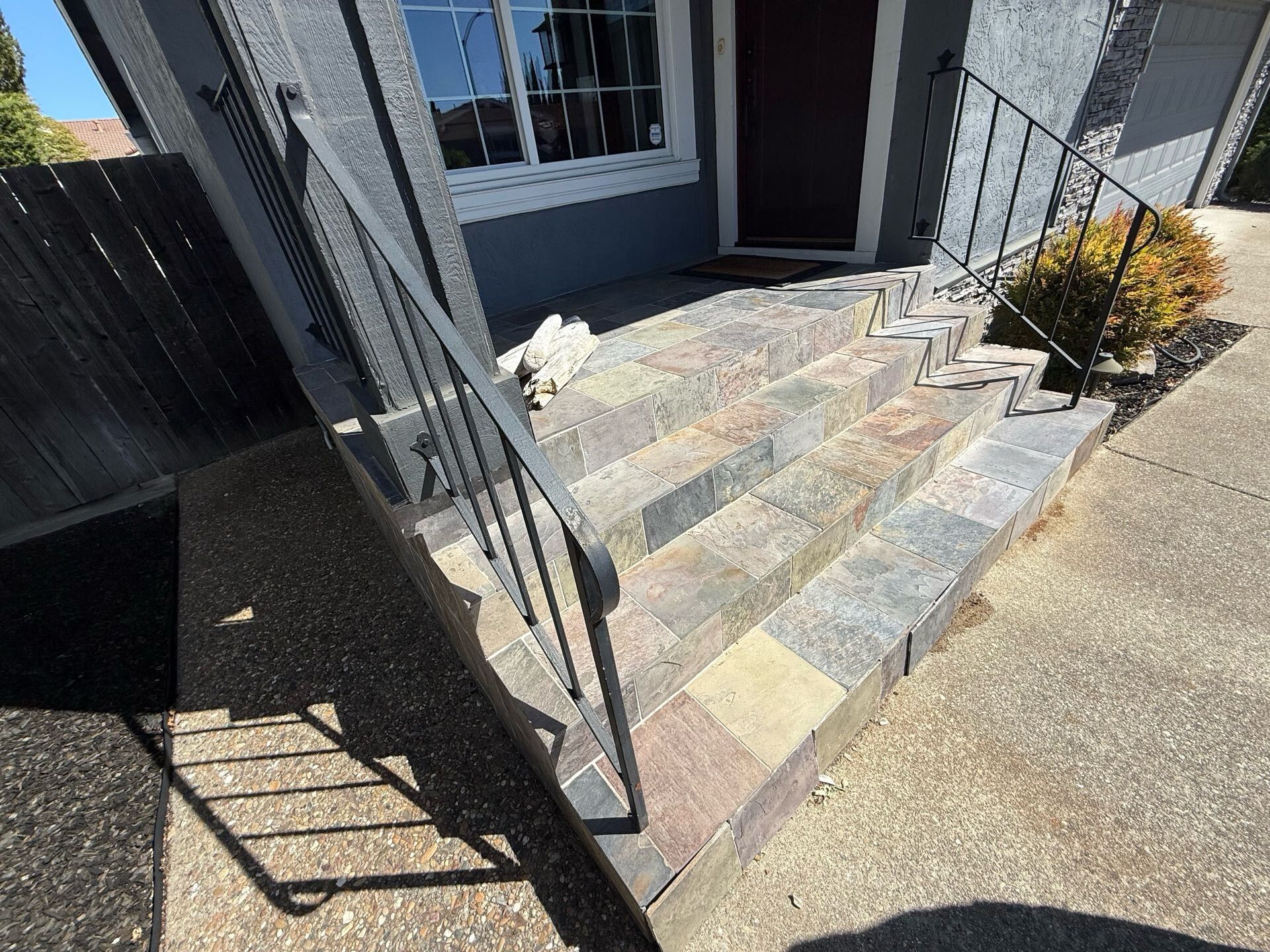 Outdoor front porch with natural slate tile steps and iron railing – original design before remodel by Dream Build Services, a Bay Area remodeling contractor.