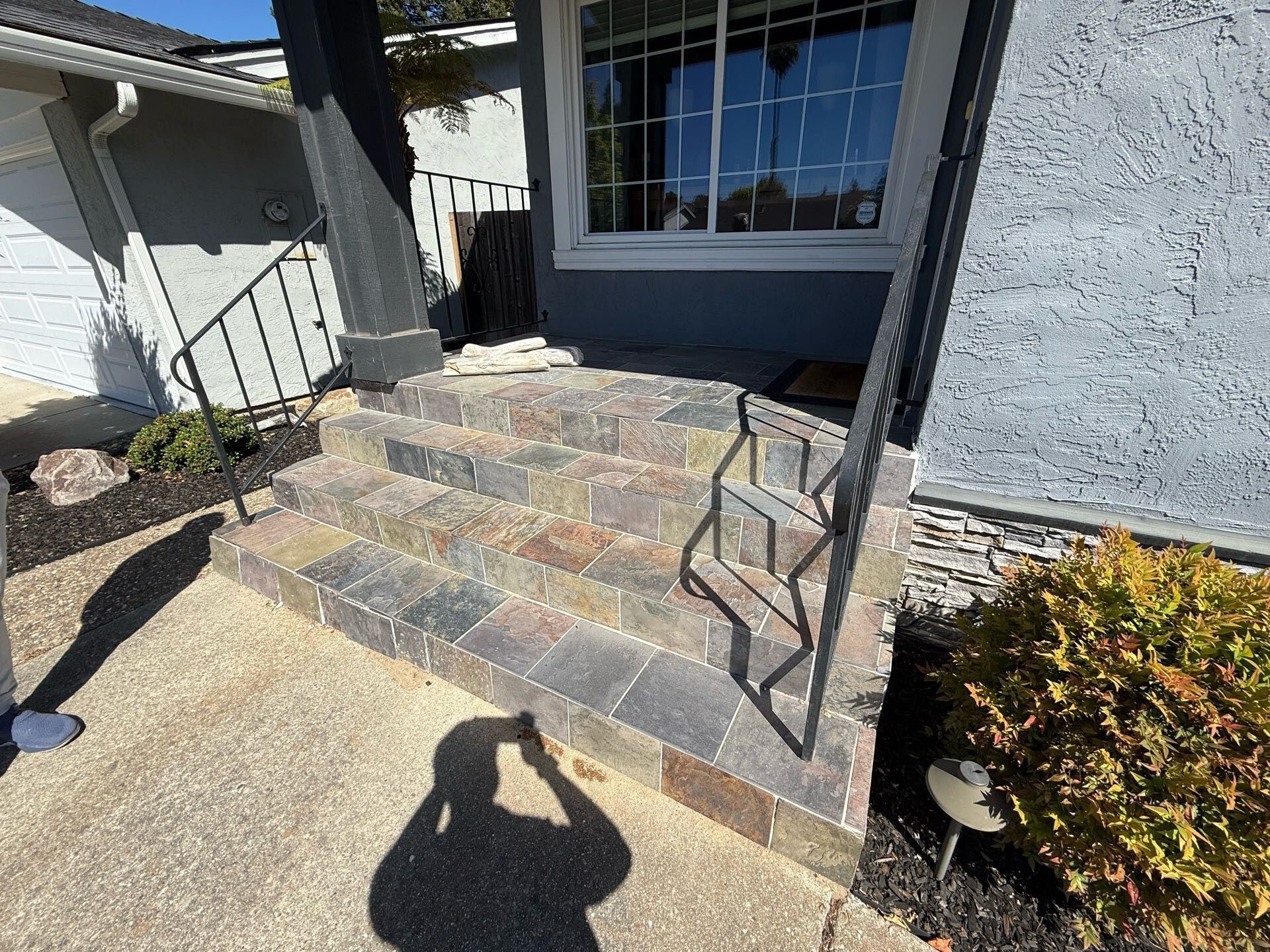 Outdoor front porch with natural slate tile steps and iron railing – original design before remodel by Dream Build Services, a Bay Area remodeling contractor.