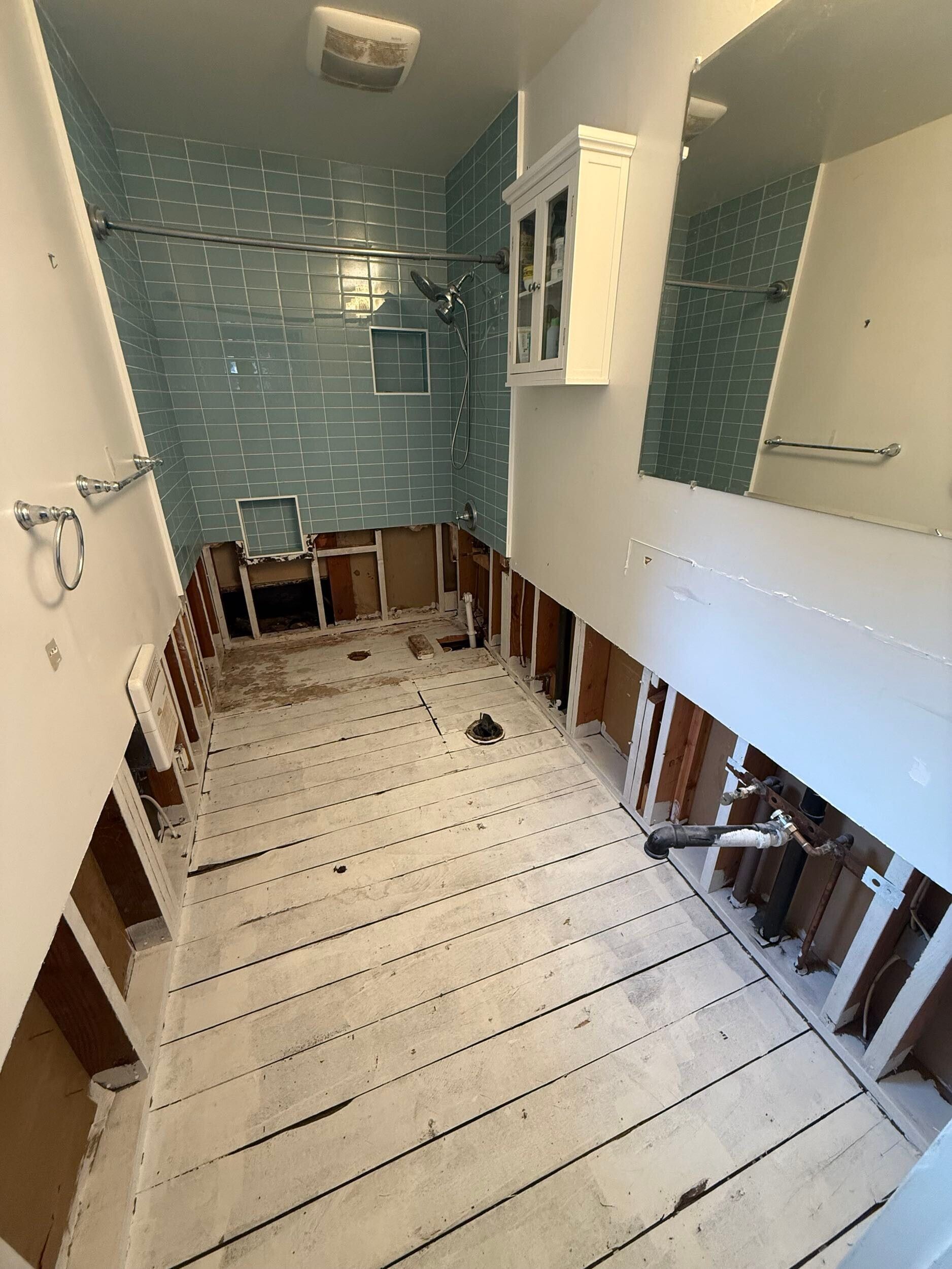 Complete bathroom remodel transformation showcasing before-and-after renovation. The updated space features a modern soaking tub with aqua subway tile walls, sleek white vanity with double sinks, bright lighting fixtures, and upgraded flooring. Project includes plumbing upgrades, custom tile shower niche, and improved storage with built-in cabinetry. Small bathroom remodel in the Bay Area with contemporary design and high-quality finishes by Dream Build Services.