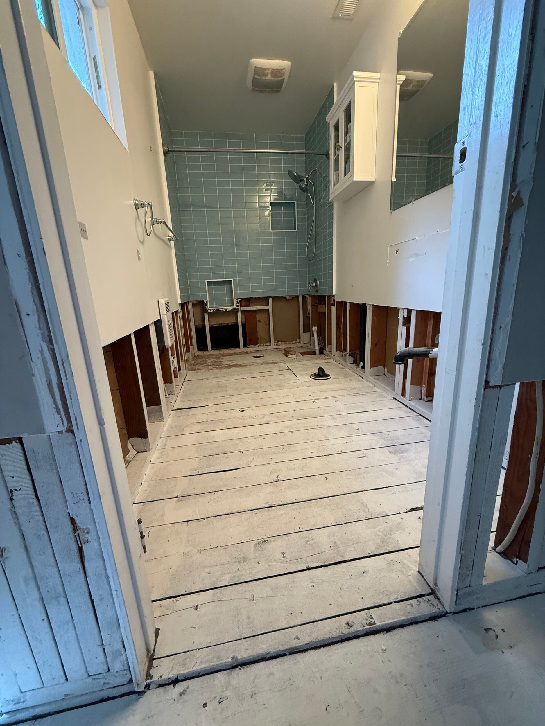 Complete bathroom remodel transformation showcasing before-and-after renovation. The updated space features a modern soaking tub with aqua subway tile walls, sleek white vanity with double sinks, bright lighting fixtures, and upgraded flooring. Project includes plumbing upgrades, custom tile shower niche, and improved storage with built-in cabinetry. Small bathroom remodel in the Bay Area with contemporary design and high-quality finishes by Dream Build Services.