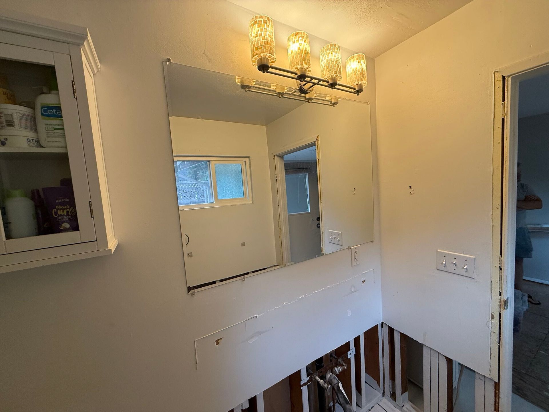 Complete bathroom remodel transformation showcasing before-and-after renovation. The updated space features a modern soaking tub with aqua subway tile walls, sleek white vanity with double sinks, bright lighting fixtures, and upgraded flooring. Project includes plumbing upgrades, custom tile shower niche, and improved storage with built-in cabinetry. Small bathroom remodel in the Bay Area with contemporary design and high-quality finishes by Dream Build Services.