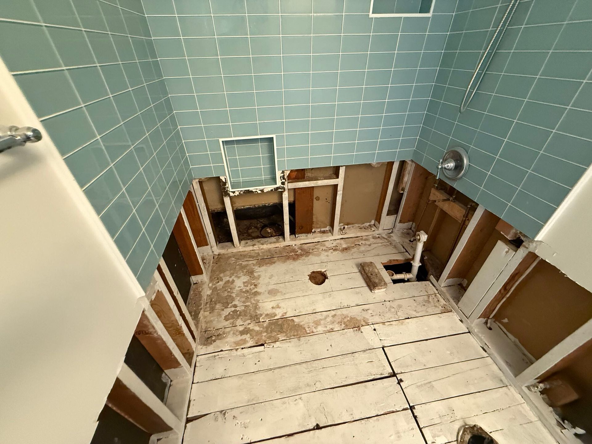 Complete bathroom remodel transformation showcasing before-and-after renovation. The updated space features a modern soaking tub with aqua subway tile walls, sleek white vanity with double sinks, bright lighting fixtures, and upgraded flooring. Project includes plumbing upgrades, custom tile shower niche, and improved storage with built-in cabinetry. Small bathroom remodel in the Bay Area with contemporary design and high-quality finishes by Dream Build Services.