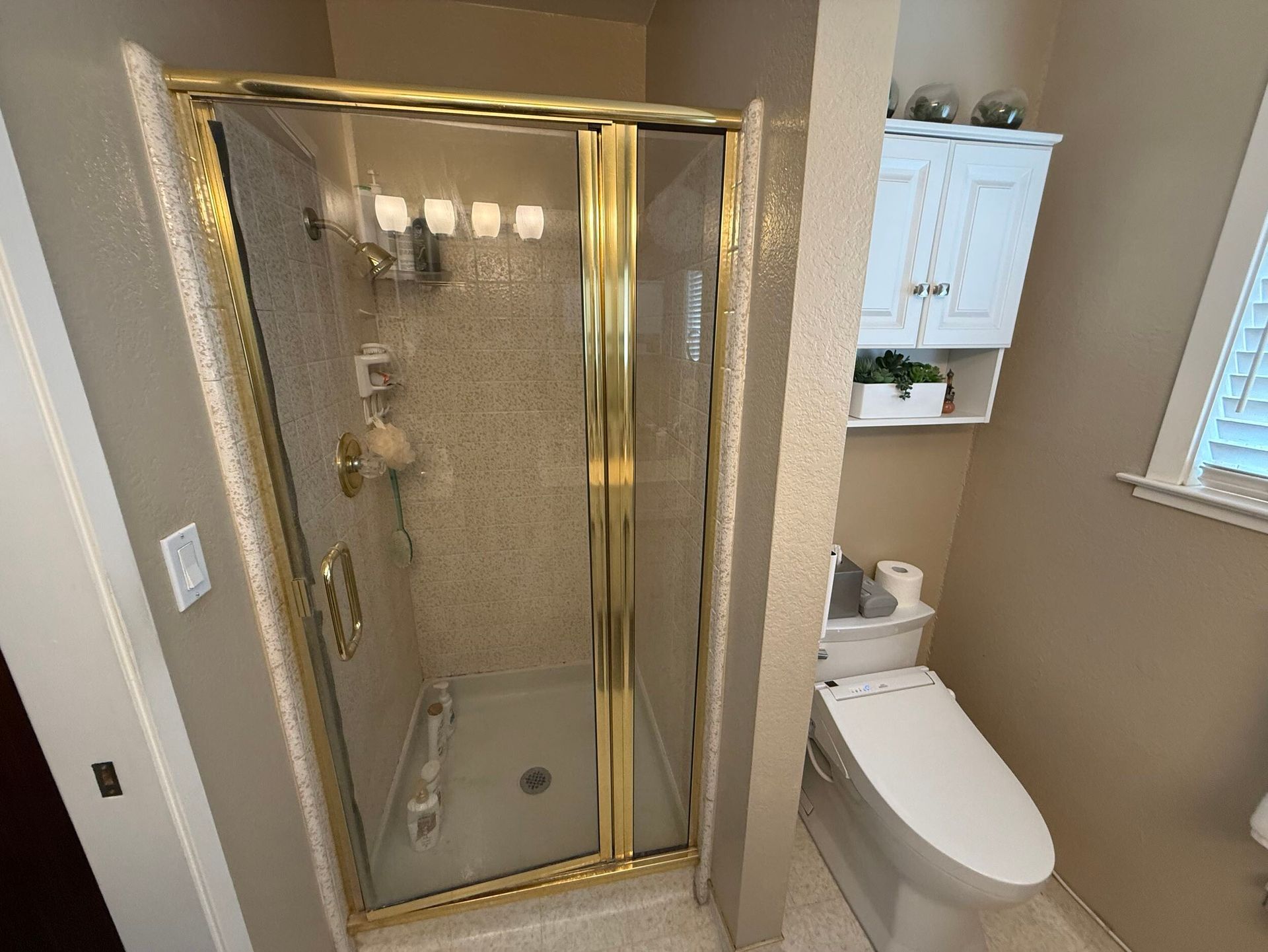 Updated bathroom remodel showcasing a modern walk-in shower with marble-style wall tile, pebble stone shower flooring, upgraded vanity with quartz countertop, contemporary sink and faucet, new lighting, and neutral color palette. Bathroom renovation completed by Dream Build Services, a residential remodeling contractor serving homeowners with bathroom and home renovation projects in the Bay Area.