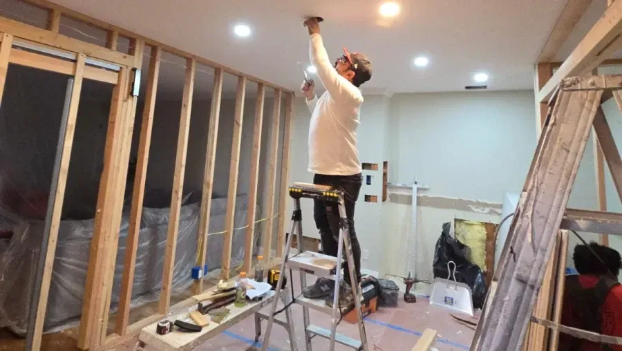 A man is standing on a ladder in a room.
