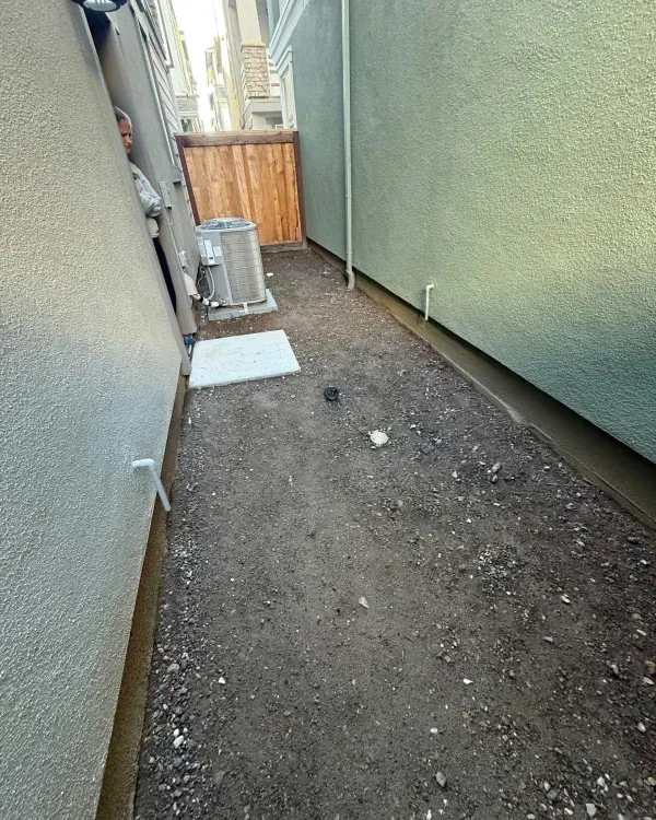 A narrow alleyway between two buildings with a wooden fence in the background.