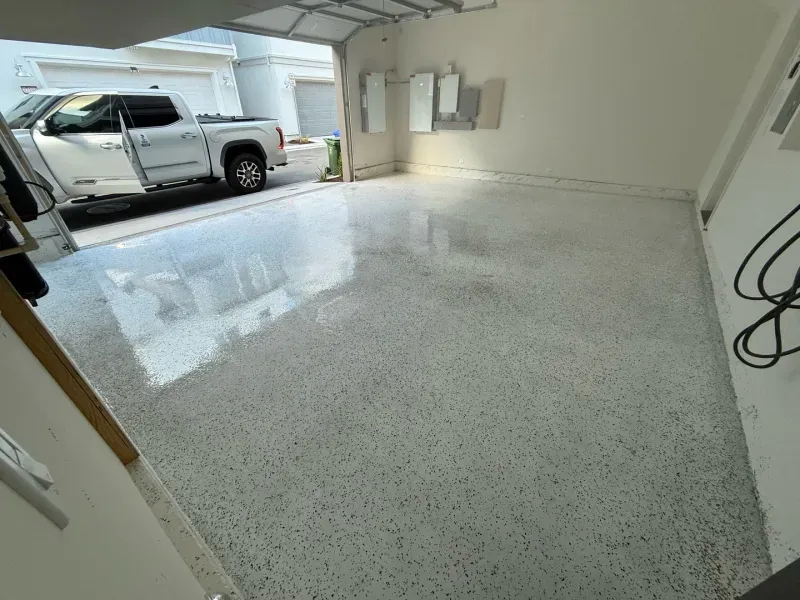 A white truck is parked in a garage with a white floor.
