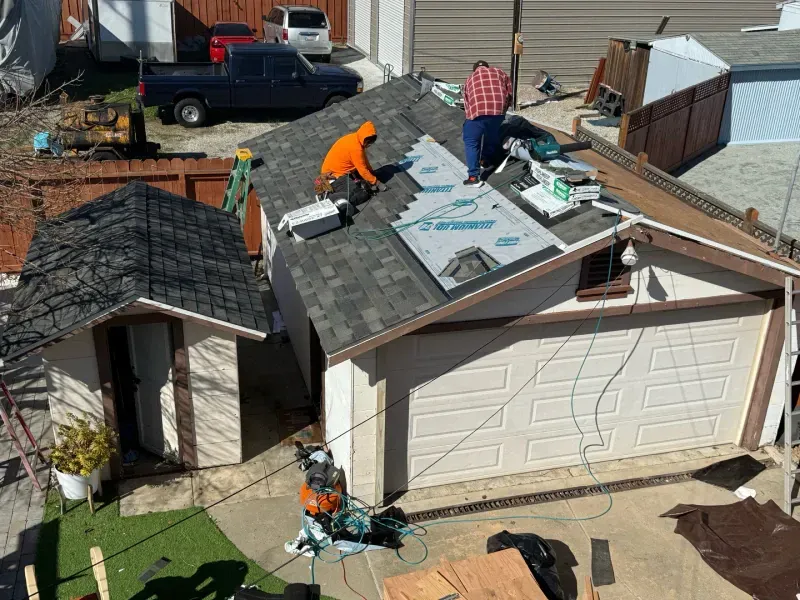 A couple of men are working on the roof of a house.