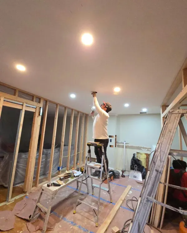 A man is standing on a ladder in a room.