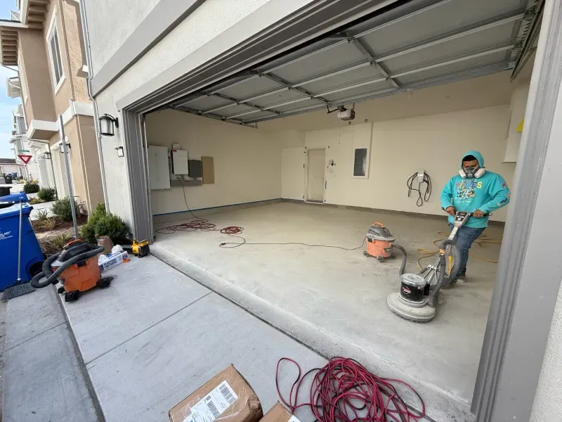 A man is cleaning the floor of a garage with a vacuum cleaner.