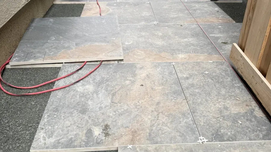 A red power cord is laying on a tiled floor.