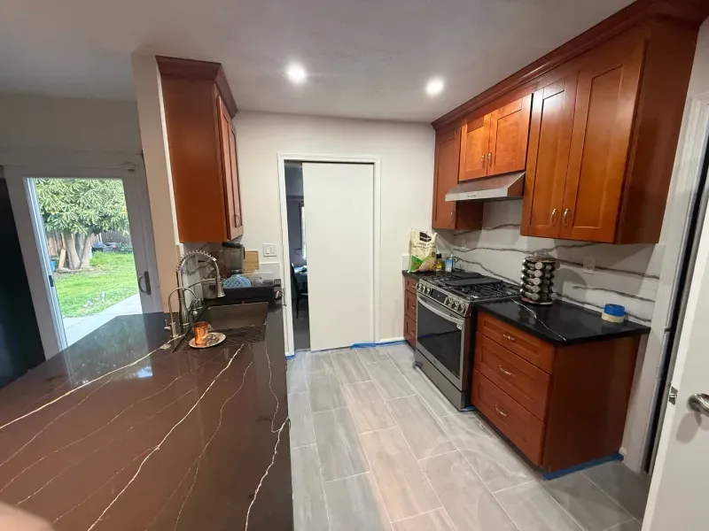 A kitchen with wooden cabinets , granite counter tops , a stove , and a sink.