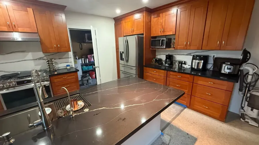 A kitchen with wooden cabinets , granite counter tops , stainless steel appliances , and a large island.