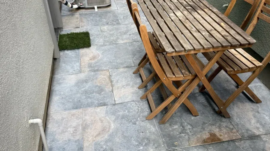 A wooden table and chairs are sitting on a patio.