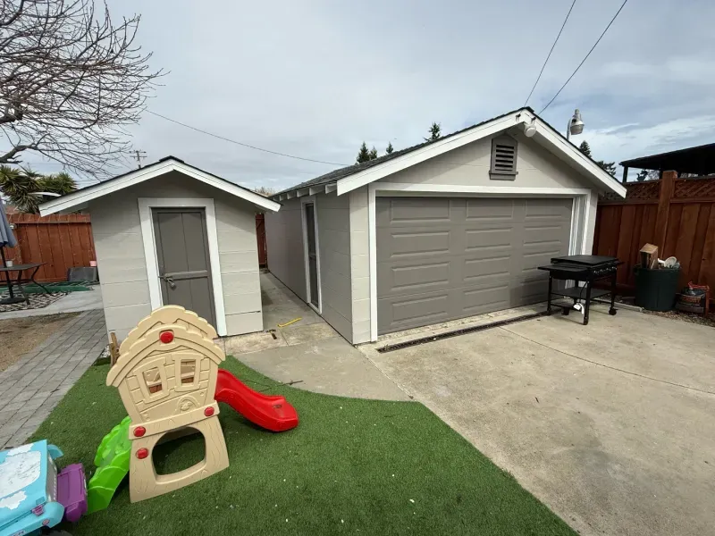 A garage with a shed and a slide in the backyard.