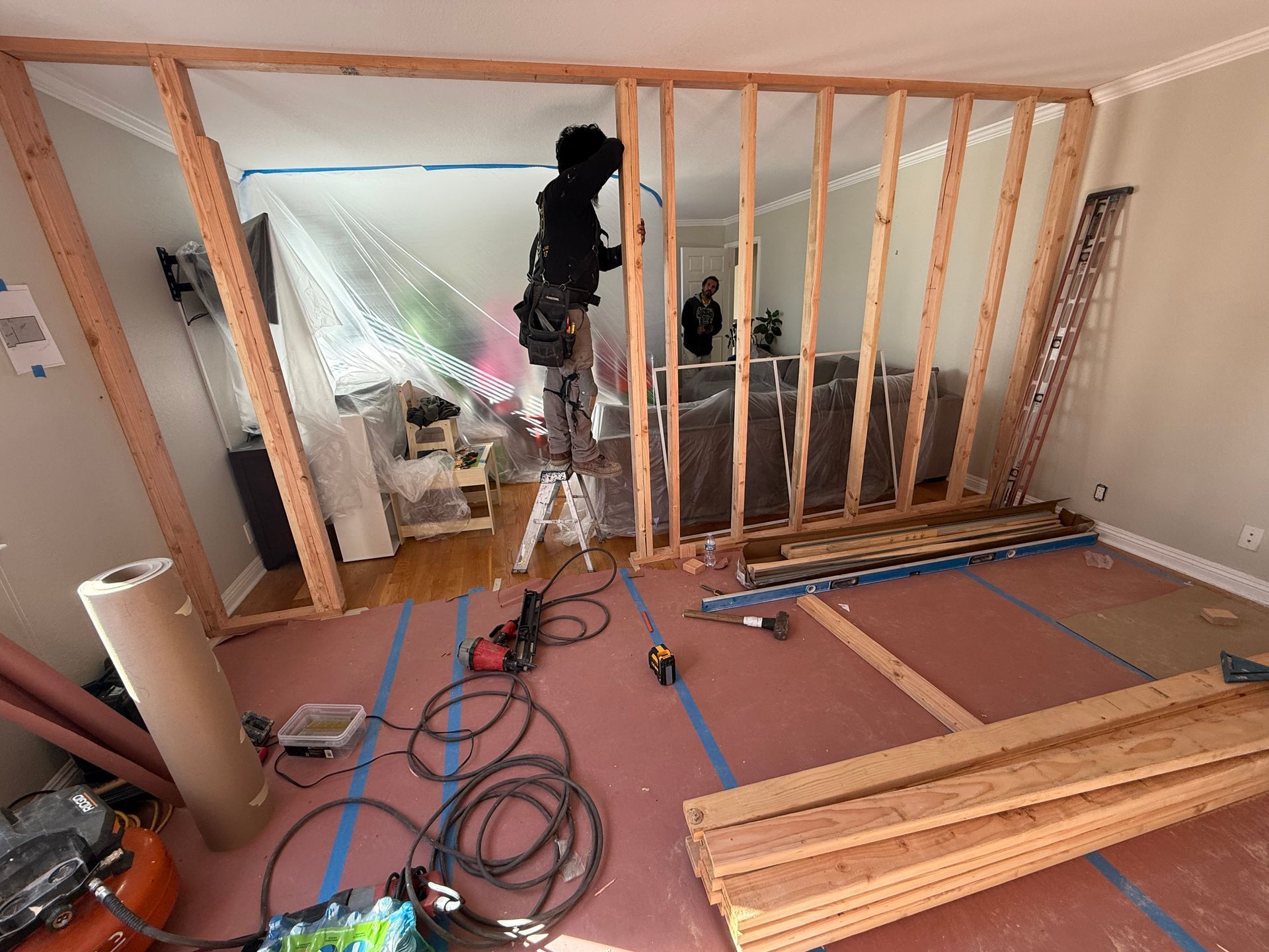 A man is working on a wall in a living room.