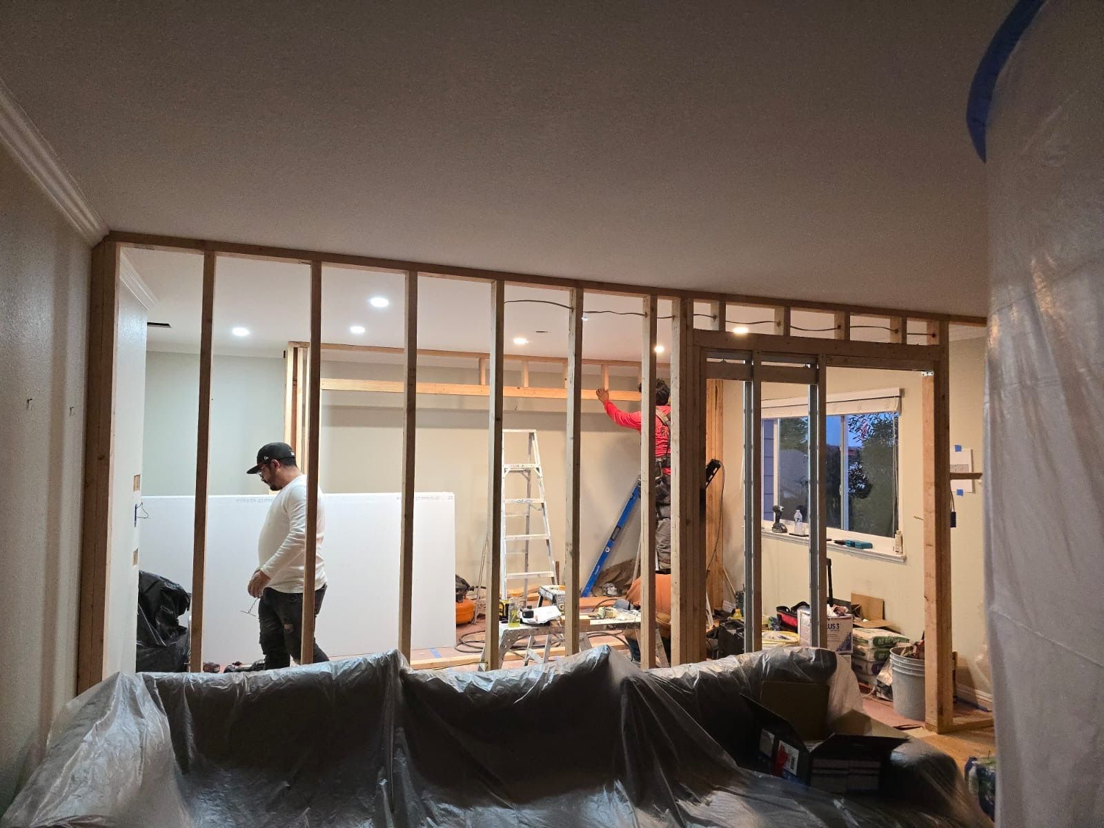 A man is working on a wall in a living room.