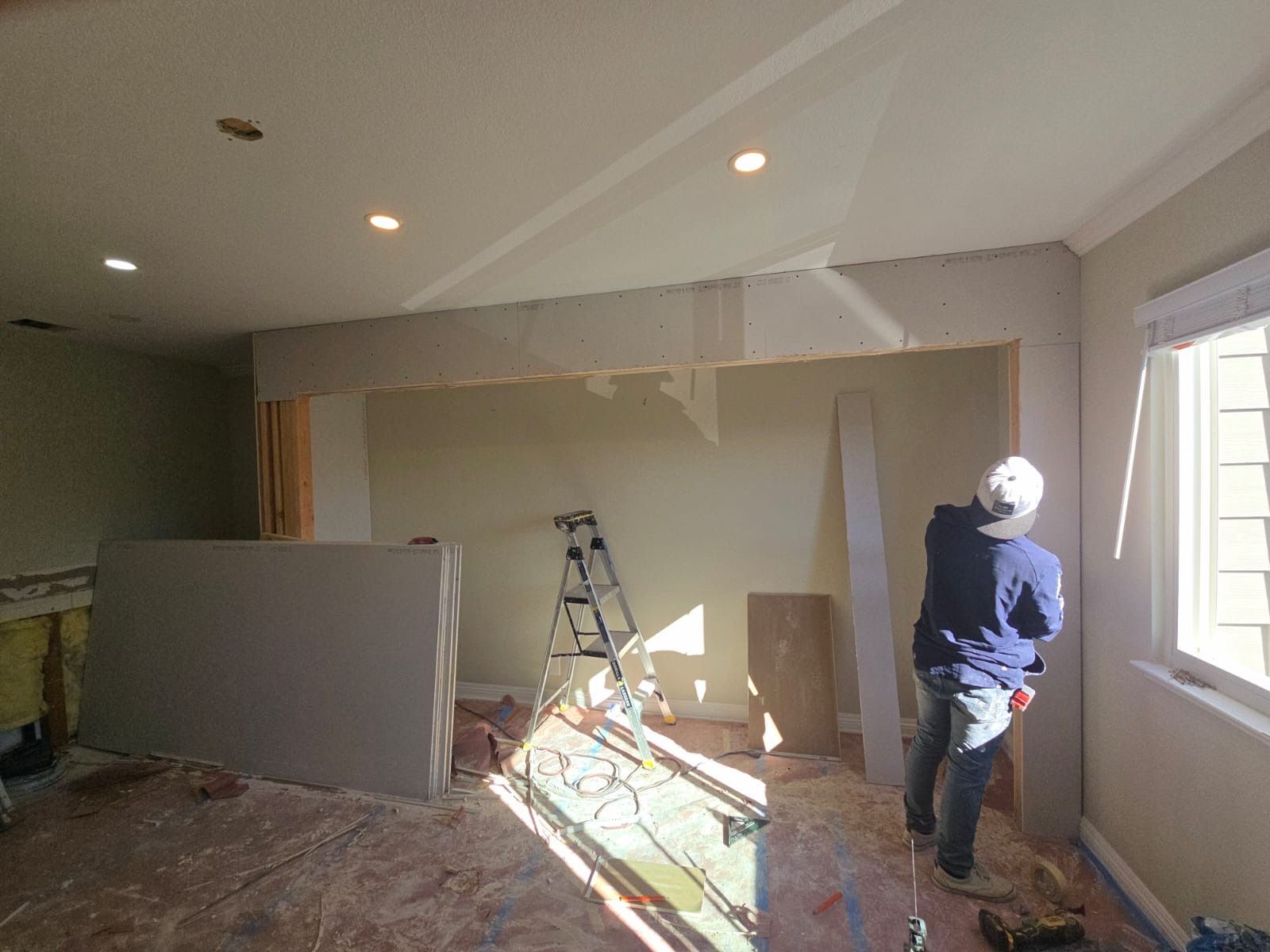 A man is standing in a room with a ladder in the background.