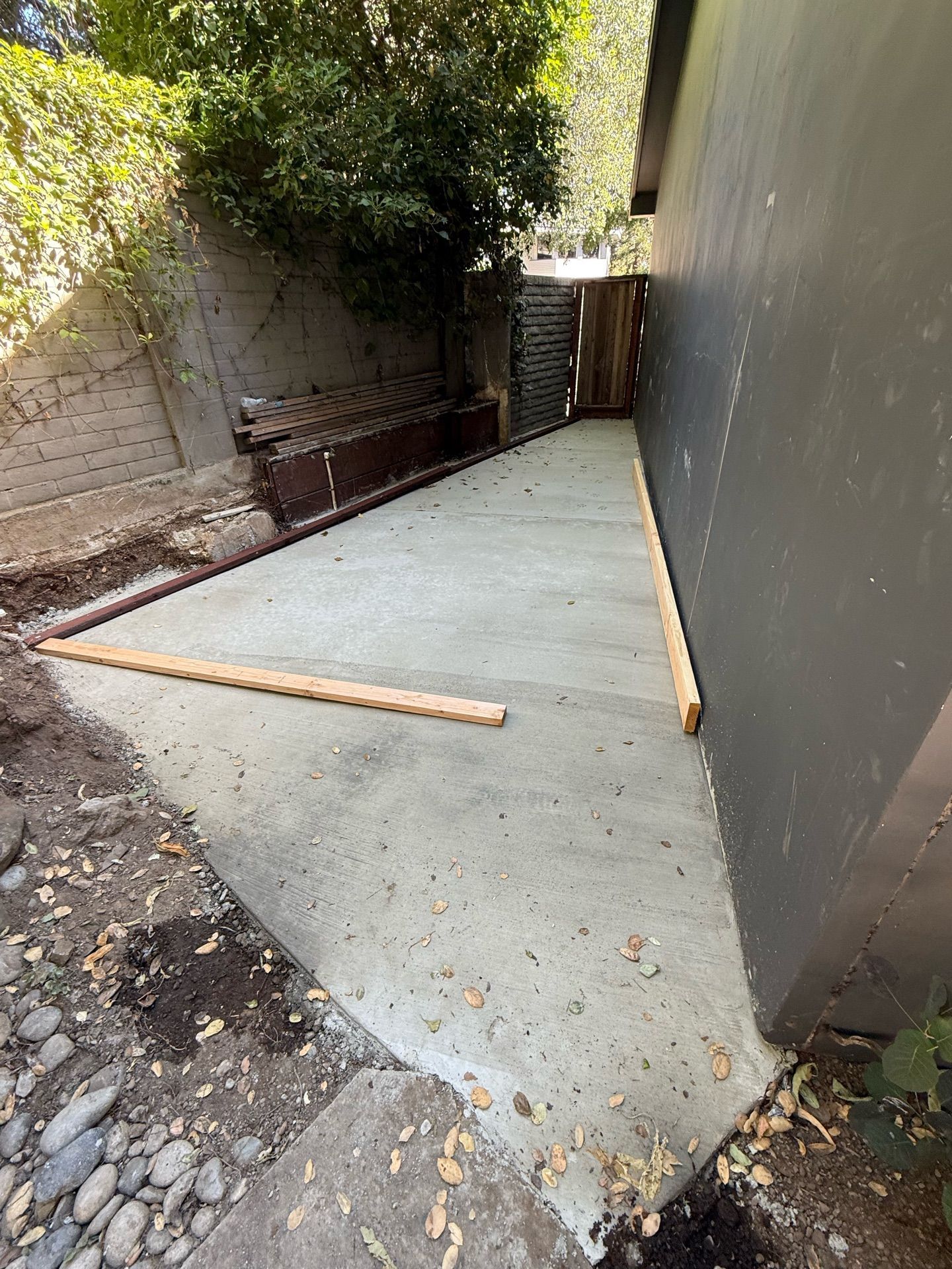 A concrete walkway is being built in the backyard of a house.
