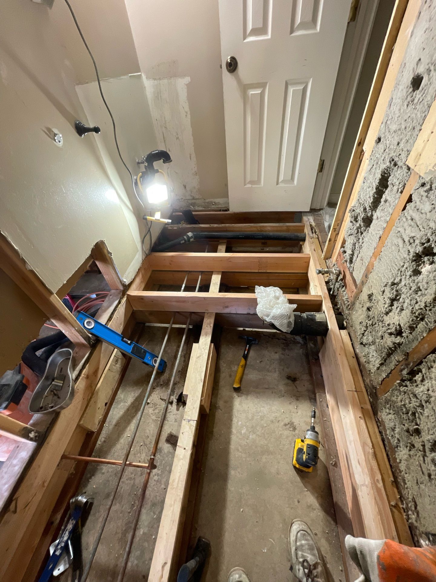 A person is standing in a room with a wooden floor and a door.