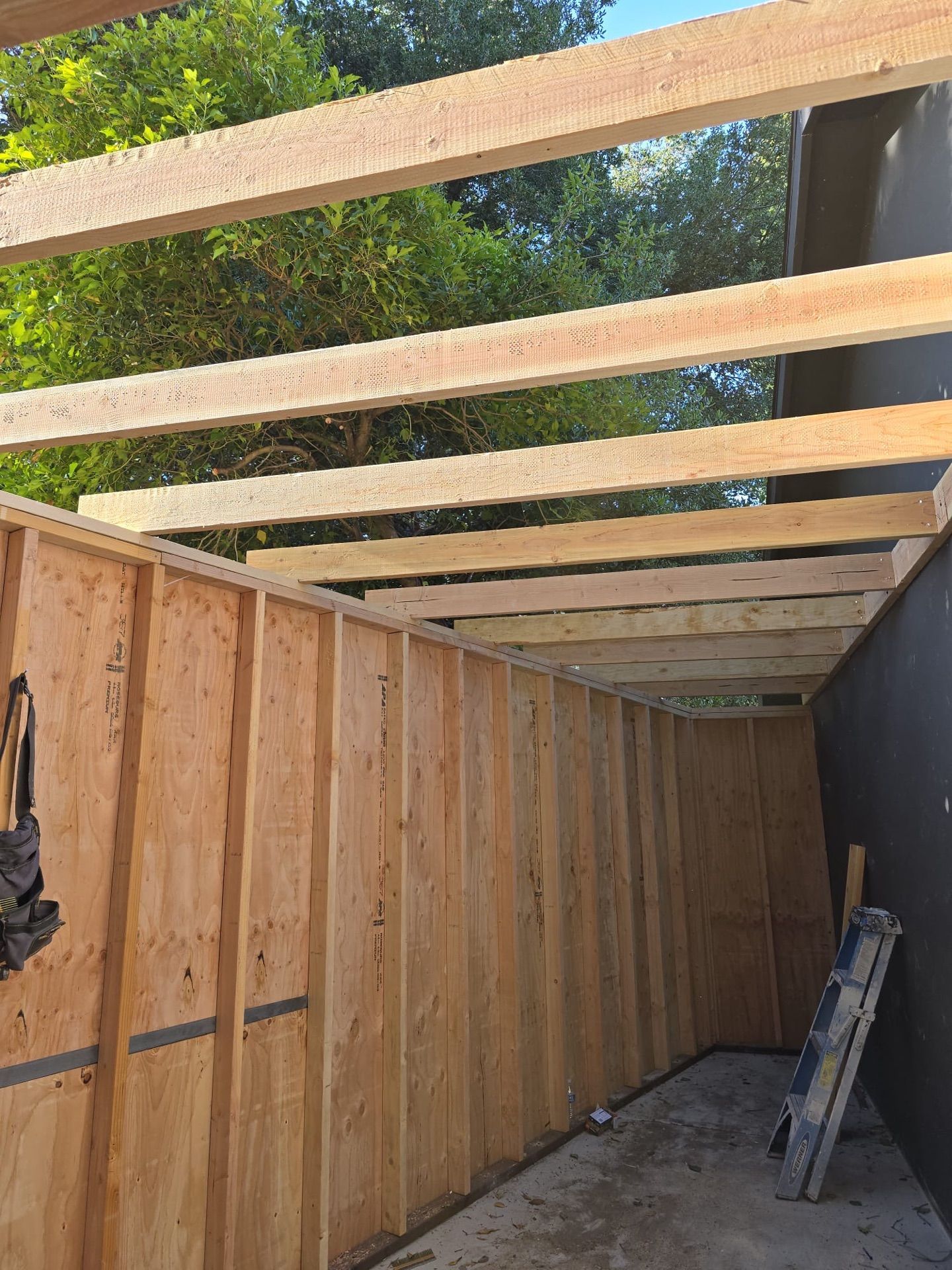 A wooden structure is being built with a ladder in the background.