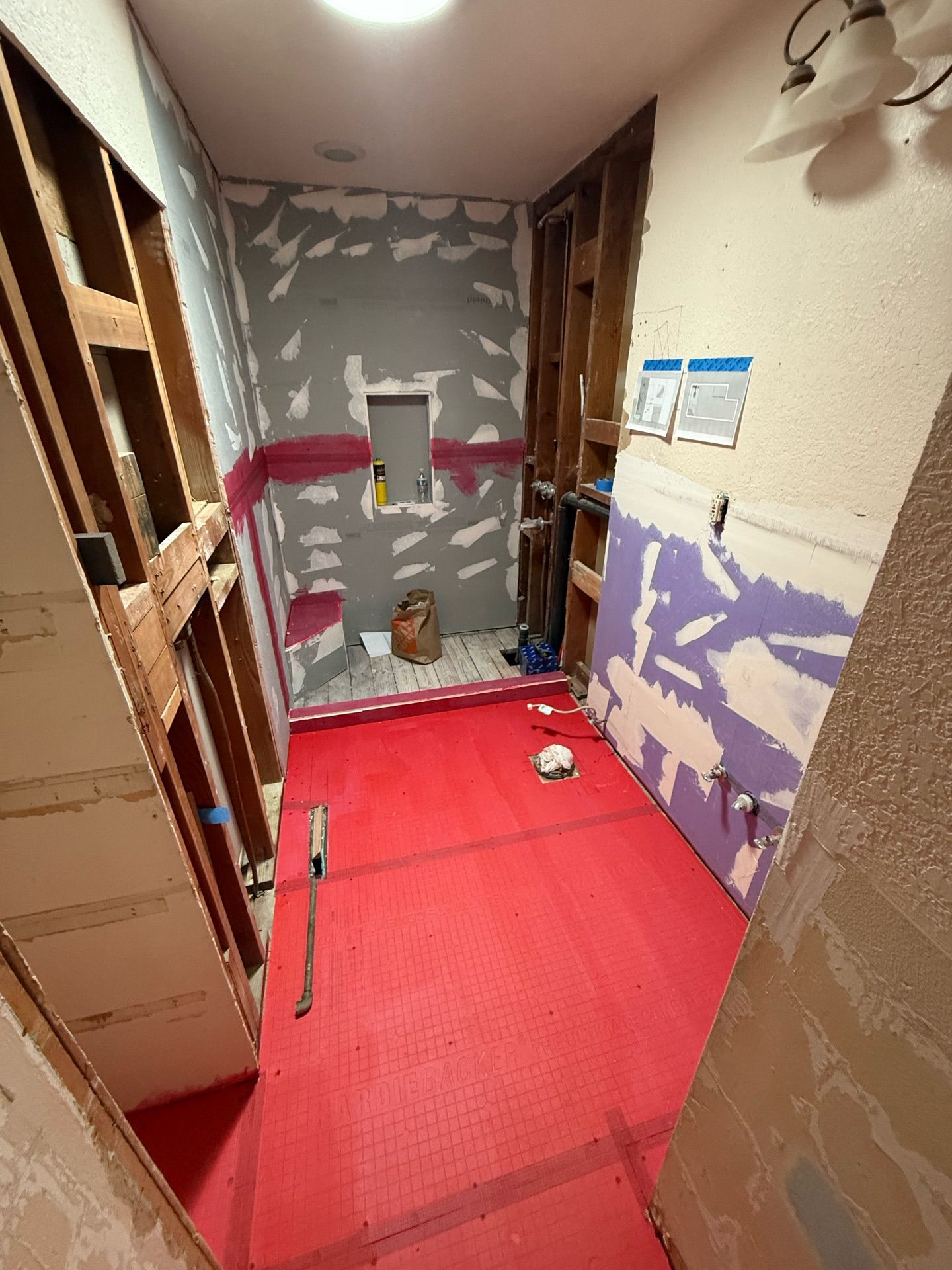 A bathroom under construction with a red mat on the floor.