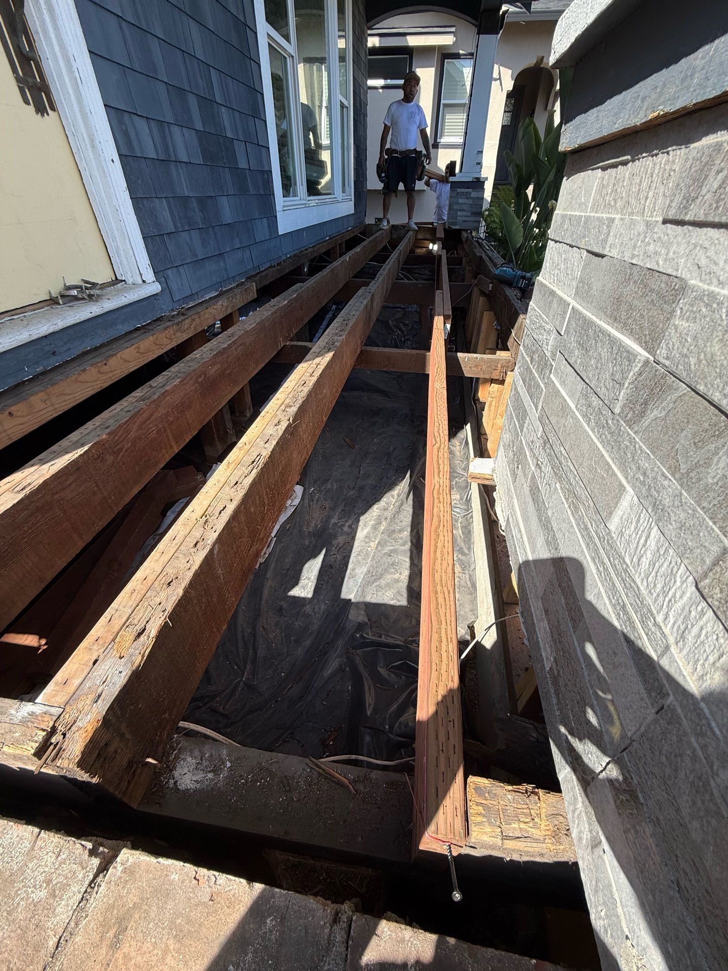 A man is standing on a wooden deck under a house.