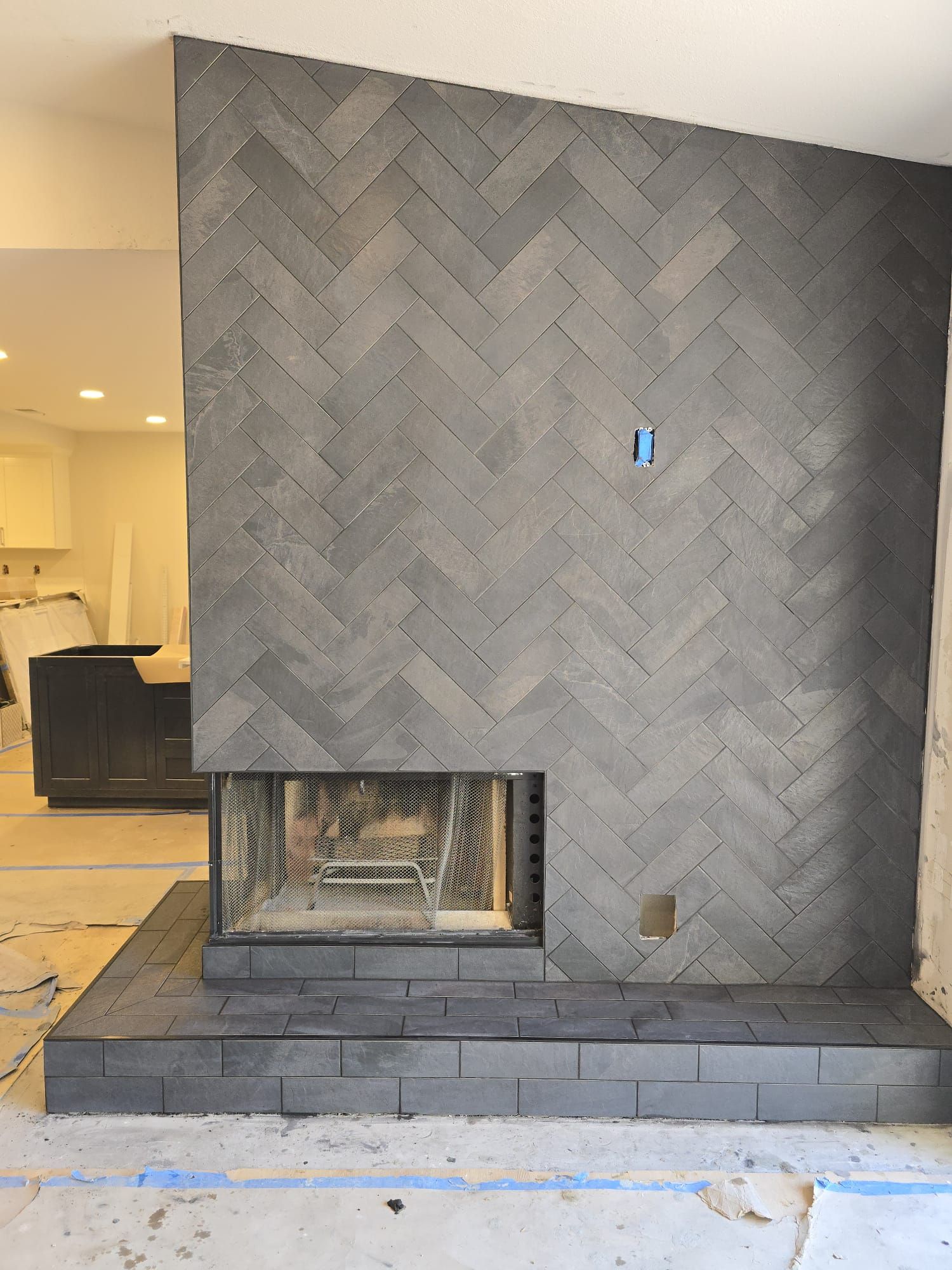 A fireplace with a herringbone pattern on the wall in a living room.